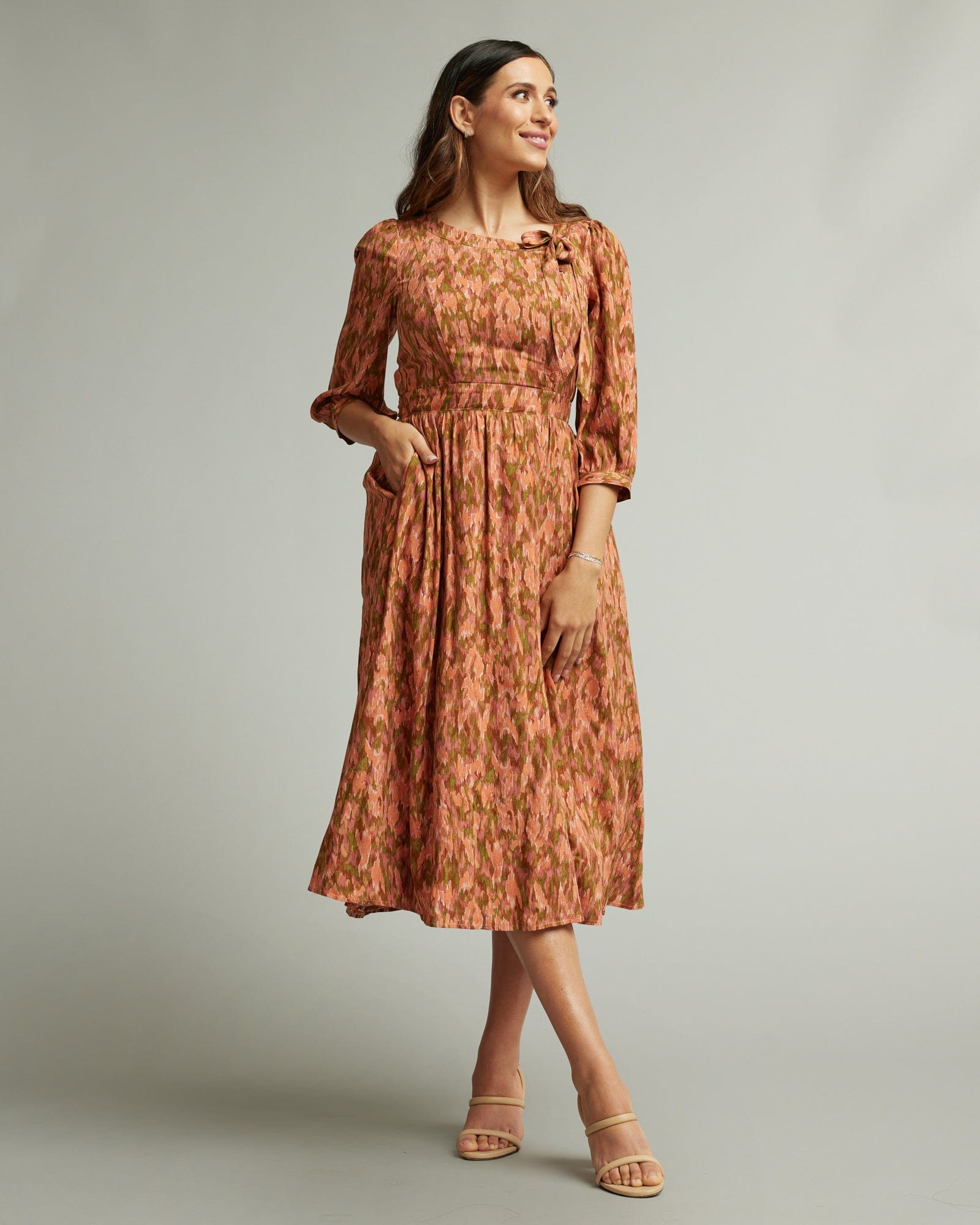 Woman in a 3/4 length sleeve, midi-length dress in orange and brown.