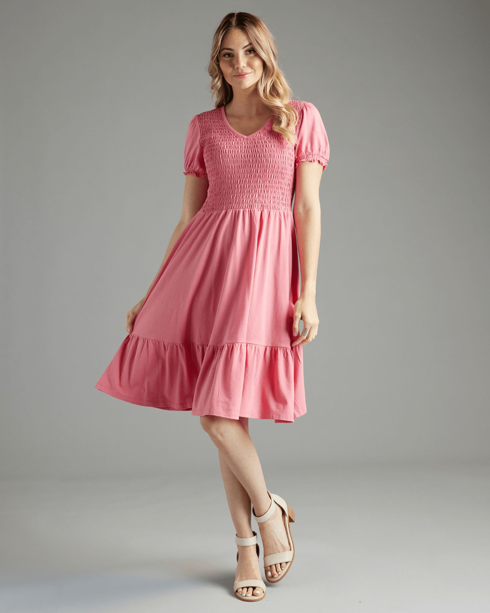 Woman in a short sleeve, knee-length, smocked bodice, pink dress