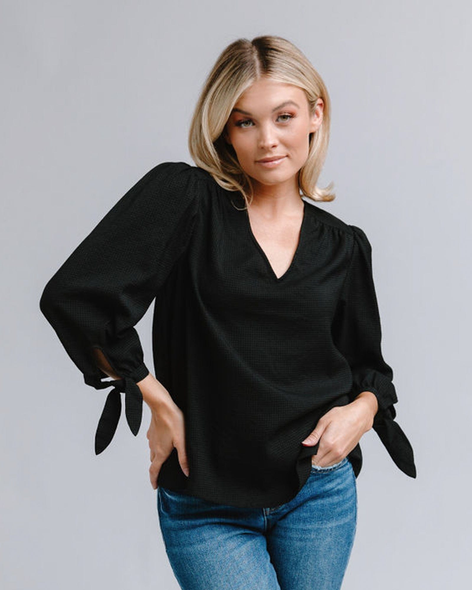 Woman in a long sleeve, v-neck, black blouse