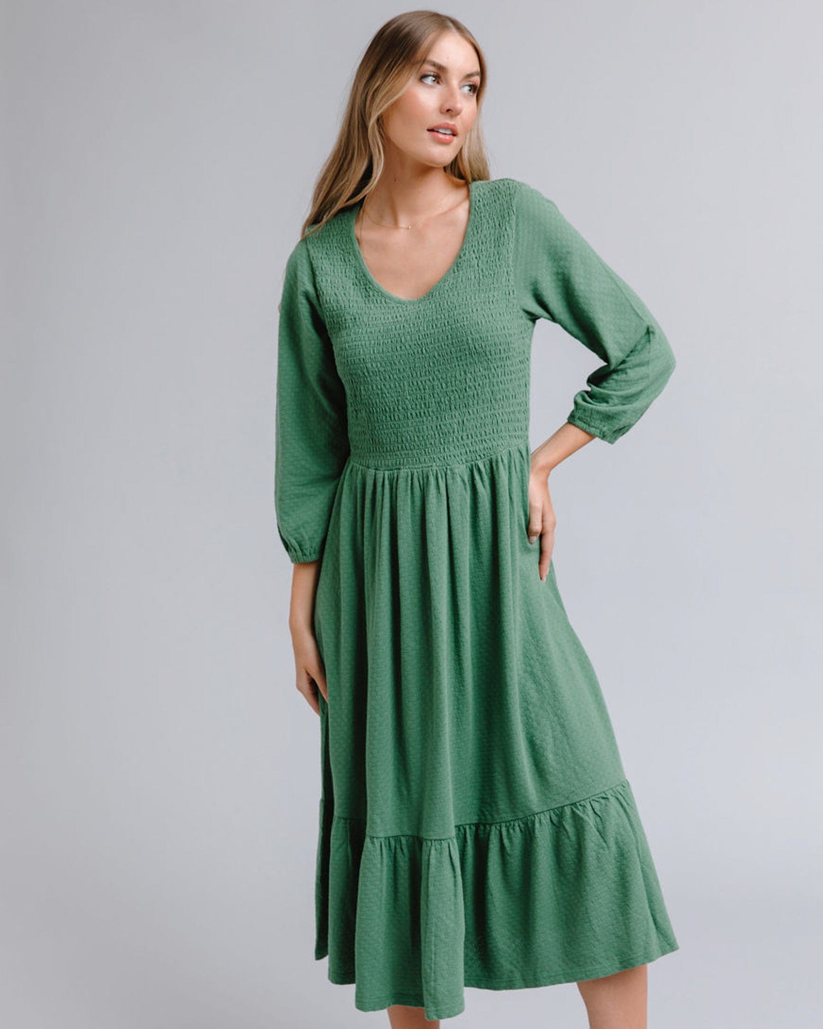 Woman in a long sleeve, midi-length, smocked bodice, green dress