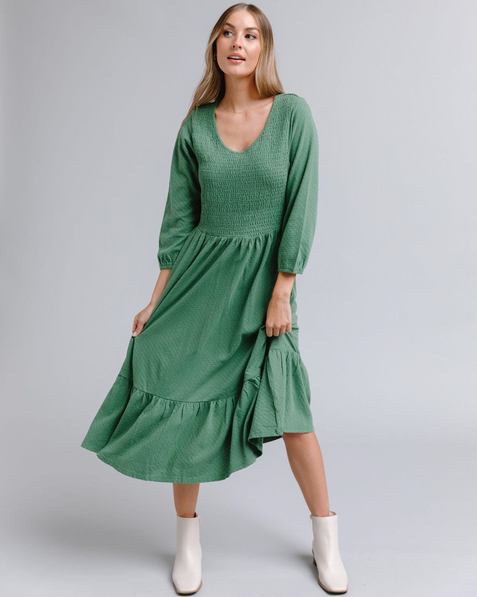 Woman in a long sleeve, midi-length, smocked bodice, green dress
