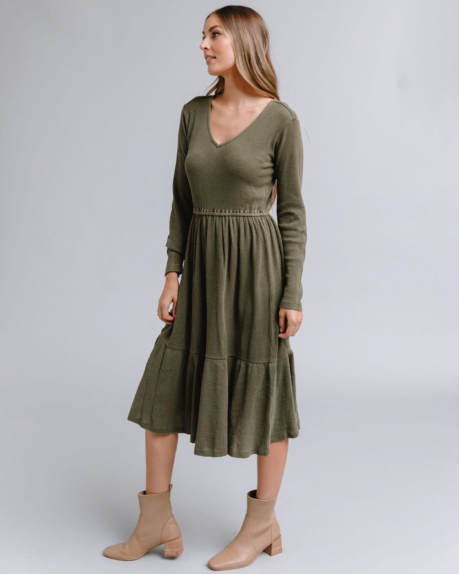 Woman in a long sleeve, v-neck, midi-length, olive green dress