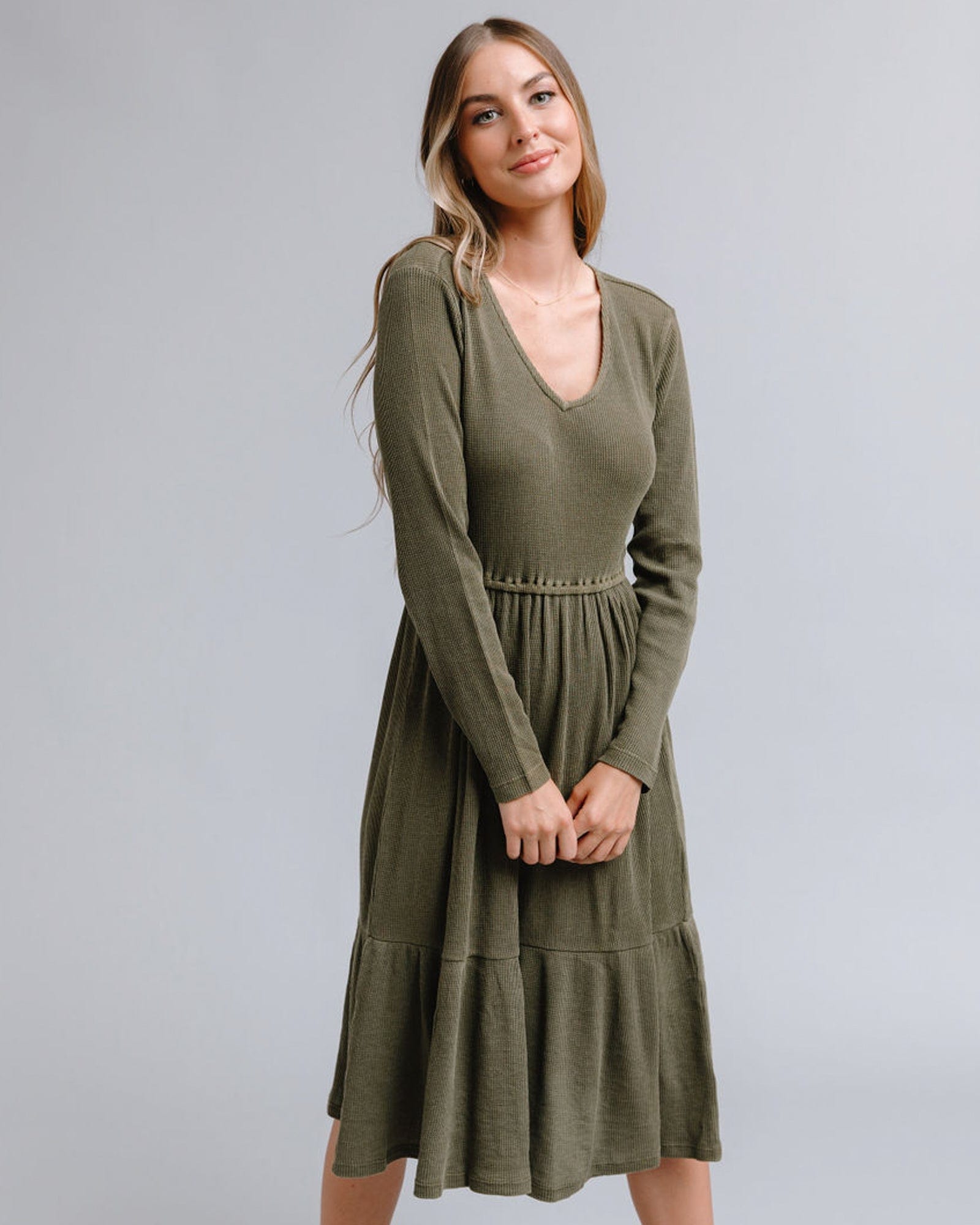 Woman in a long sleeve, v-neck, midi-length, olive green dress