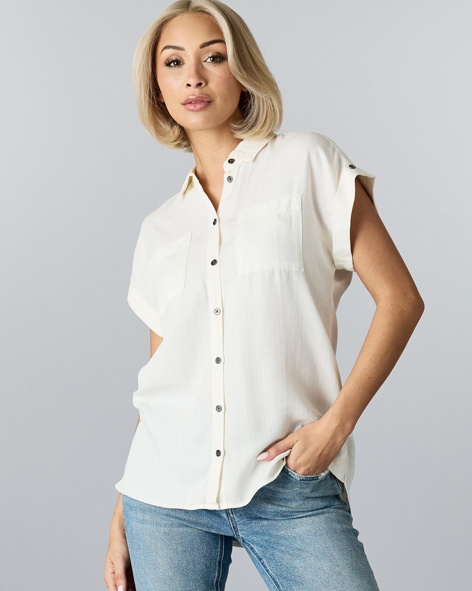 Woman in a short sleeved, button-down blouse with a collar and two chest pockets.