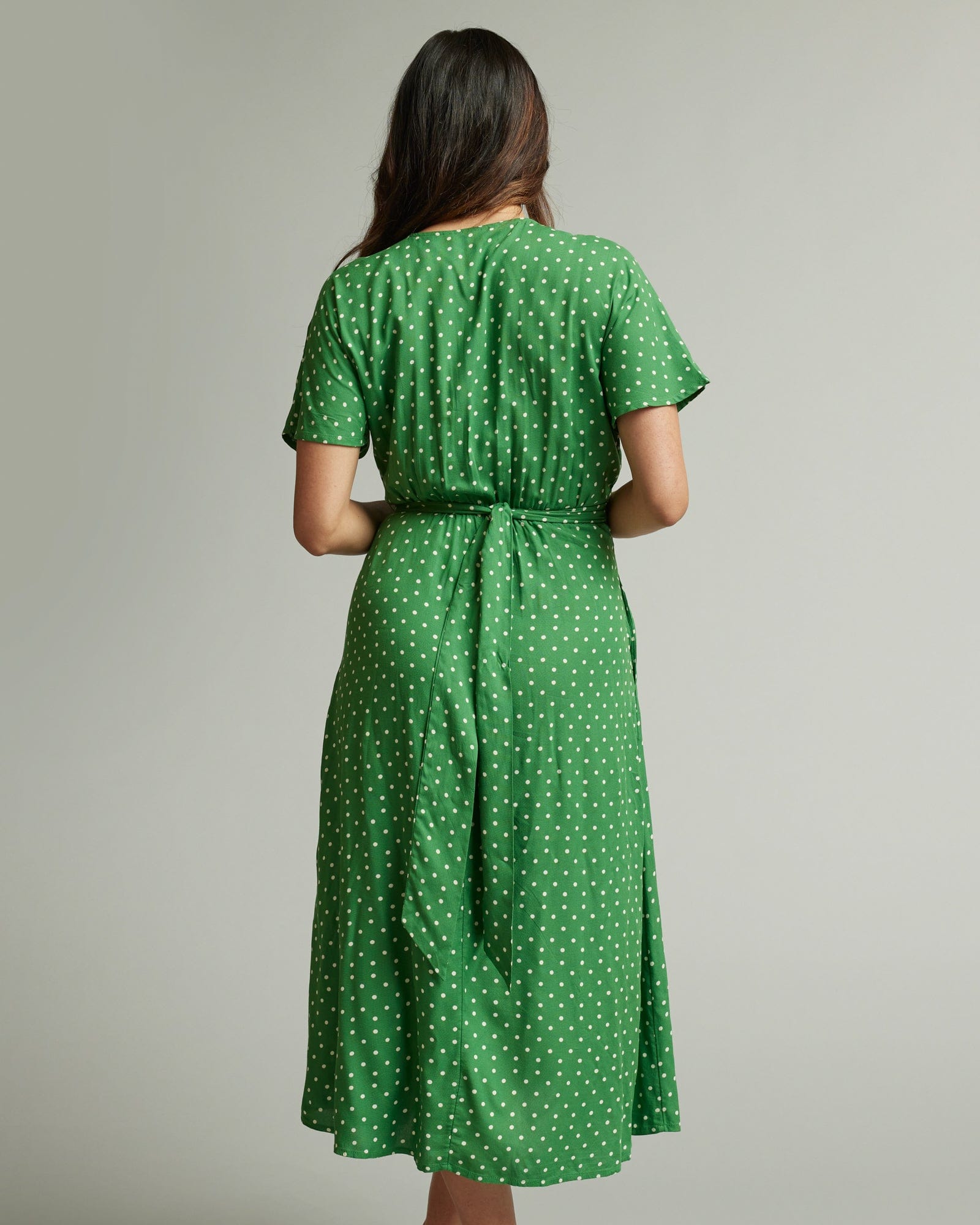Woman in a short sleeve, midi-length, green with white polka dotted dress