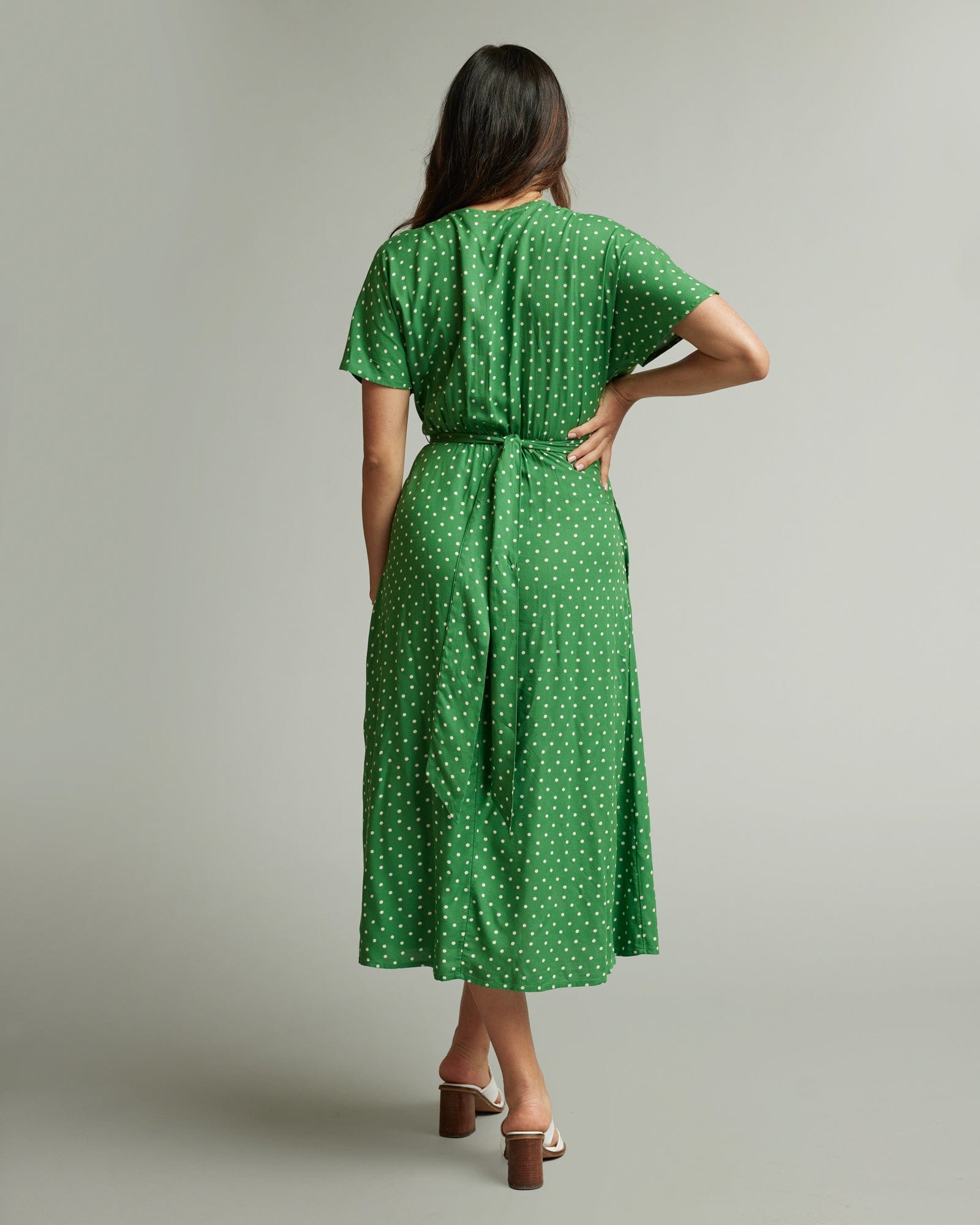 Woman in a short sleeve, midi-length, green with white polka dotted dress