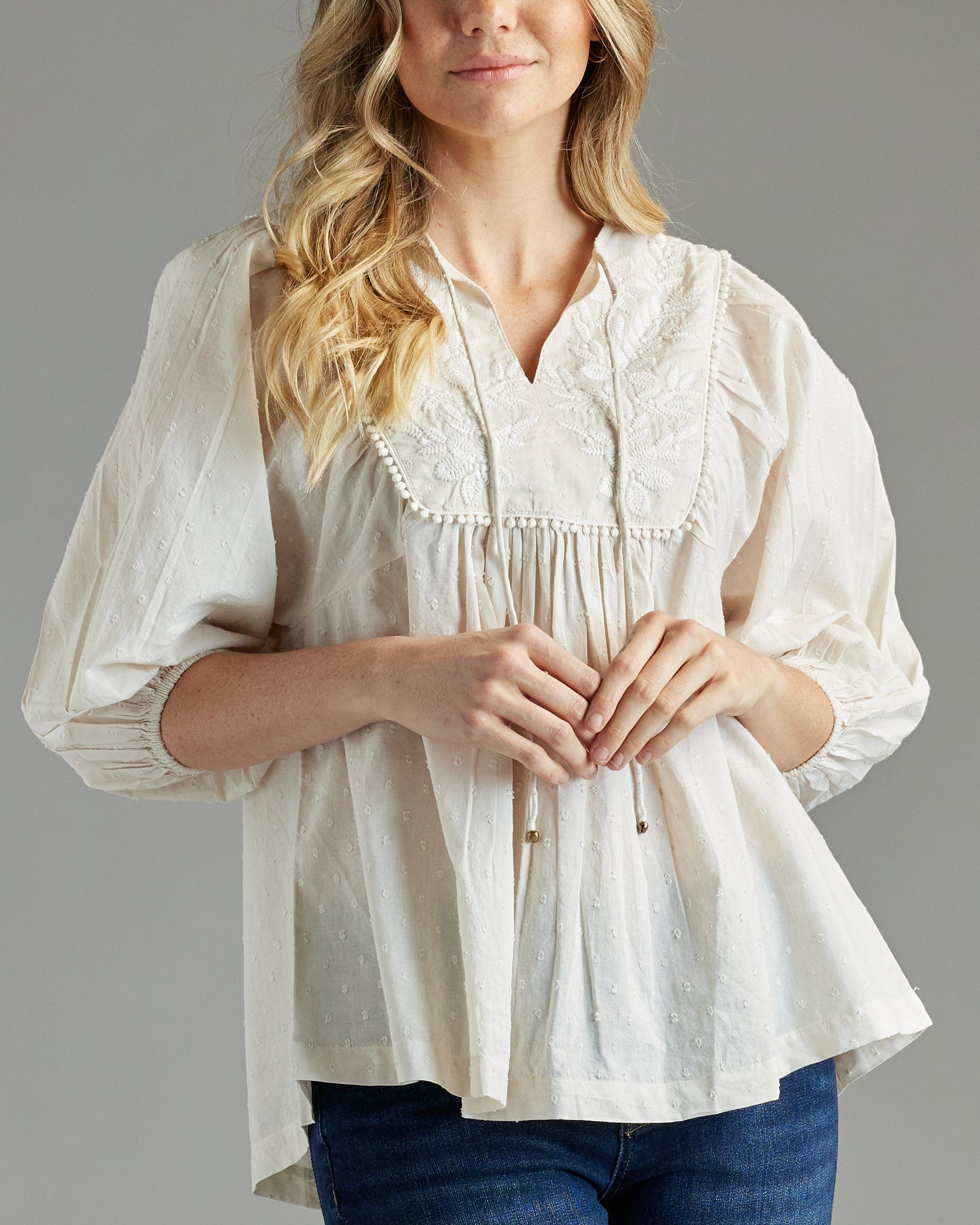 Woman in a white blouse with 3/4 length sleeves and embroidery on bib