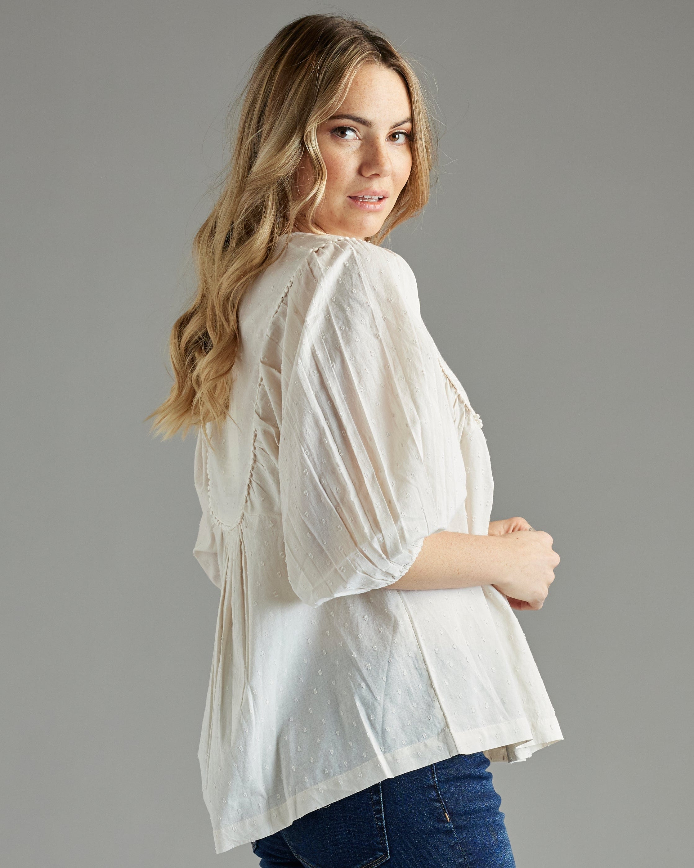 Woman in a white blouse with 3/4 length sleeves and embroidery on bib