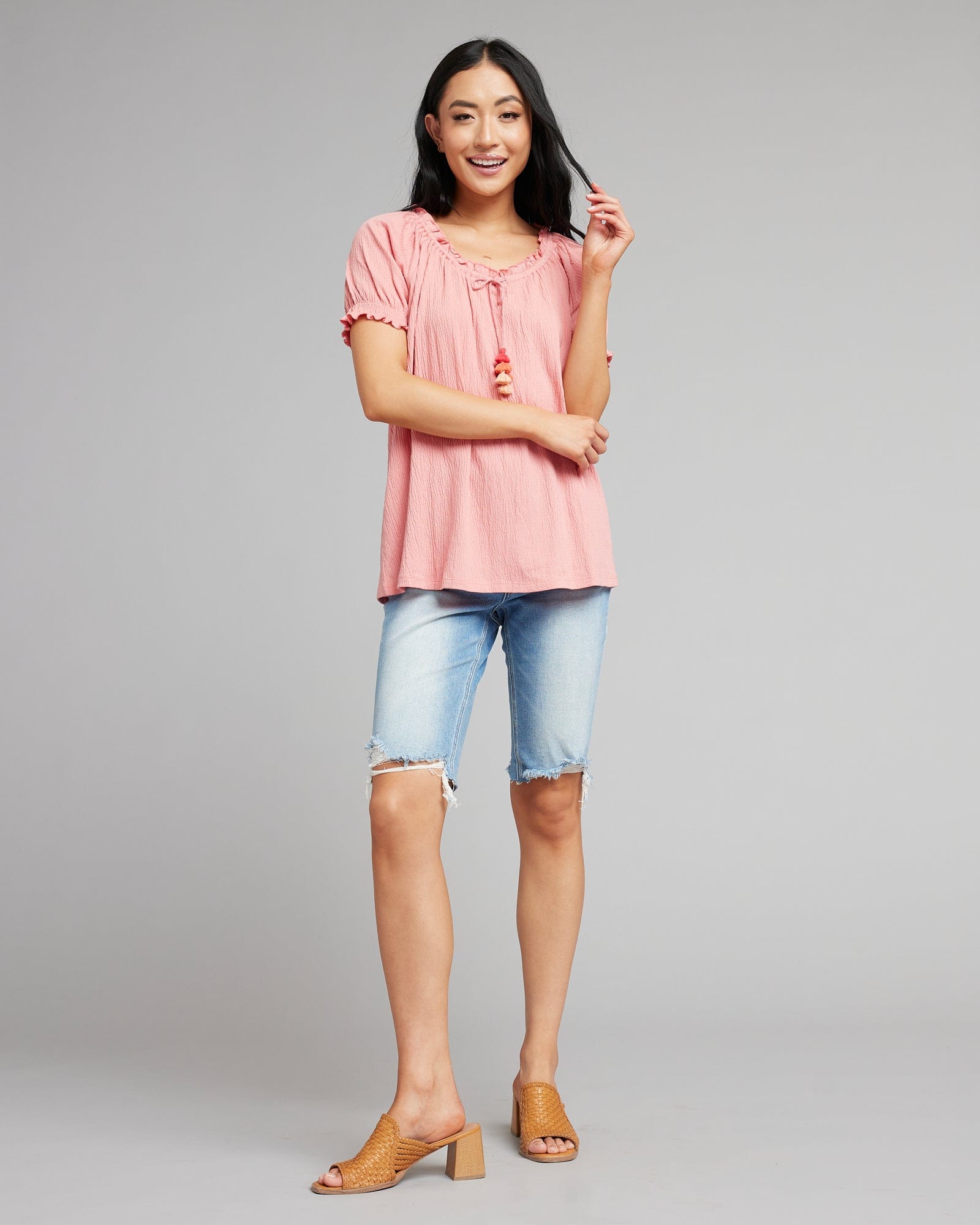 Women in a pink short sleeve blouse with tassels at neckline