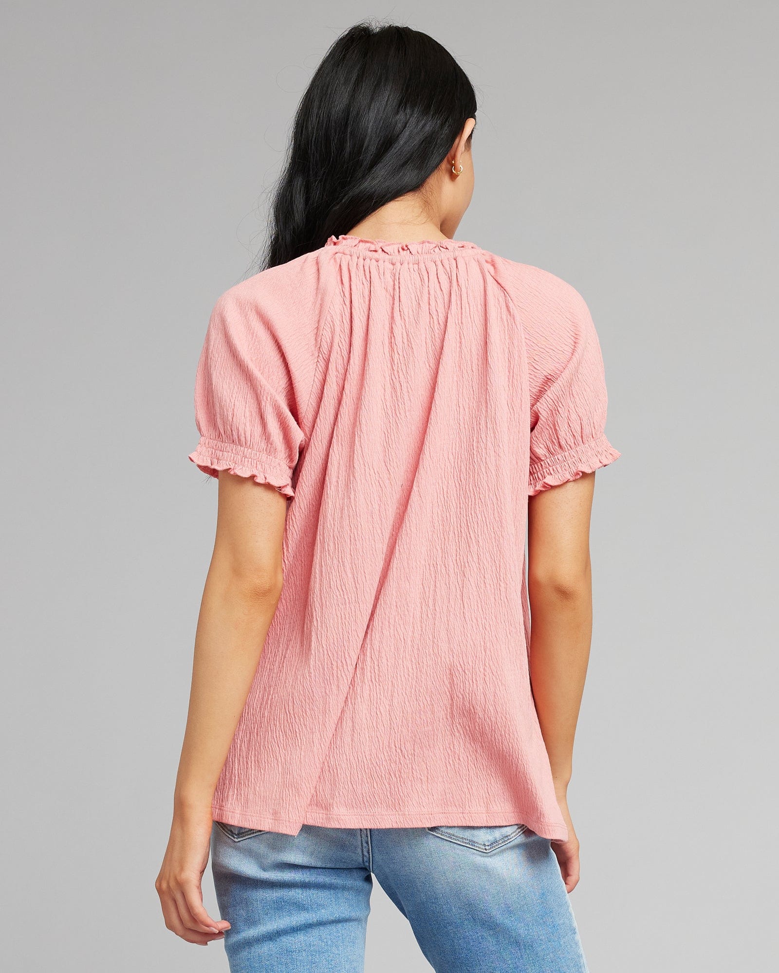 Women in a pink short sleeve blouse with tassels at neckline