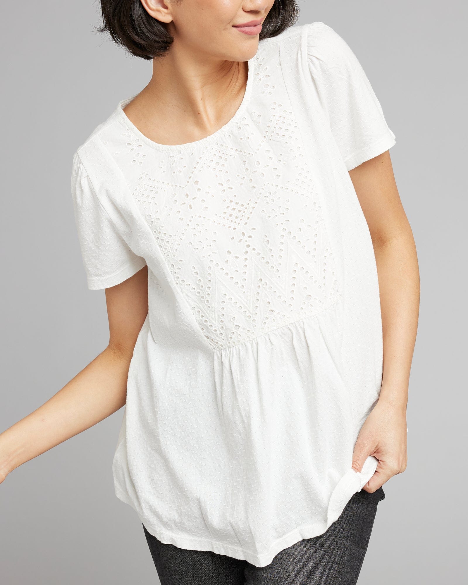 Woman in a white, short sleeved, top with eyelet motif on front