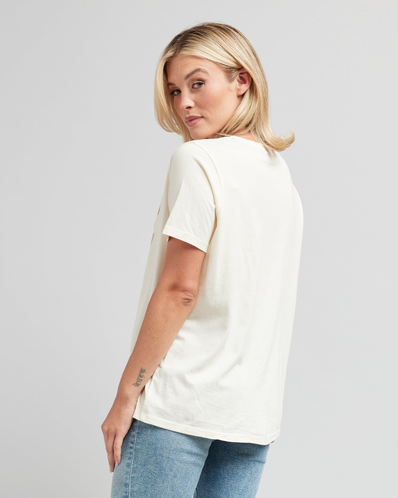 Woman in a short sleeve, white graphic tee that says "Keep Going"