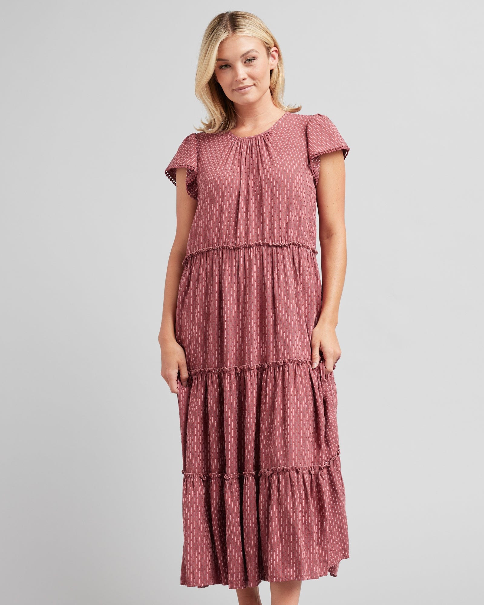 Woman in a short sleeve, midi-length, tiered skirt, pink dress
