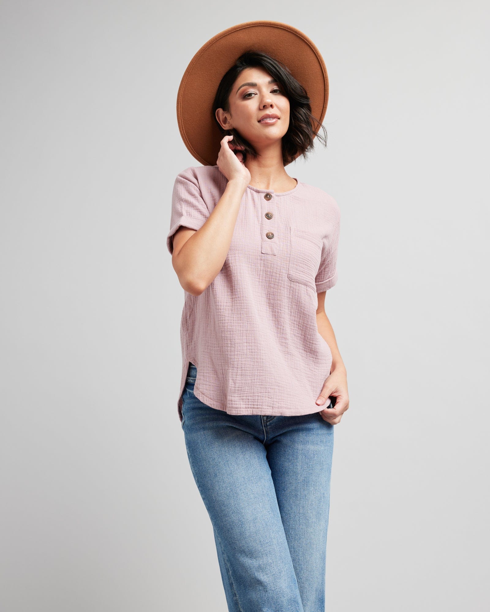 Woman in a short cuffed sleeve blouse with buttons at neckline and a front pocket