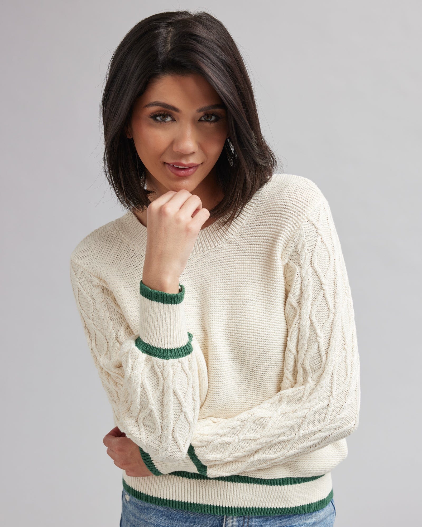Woman in a cream colored sweater with green accents
