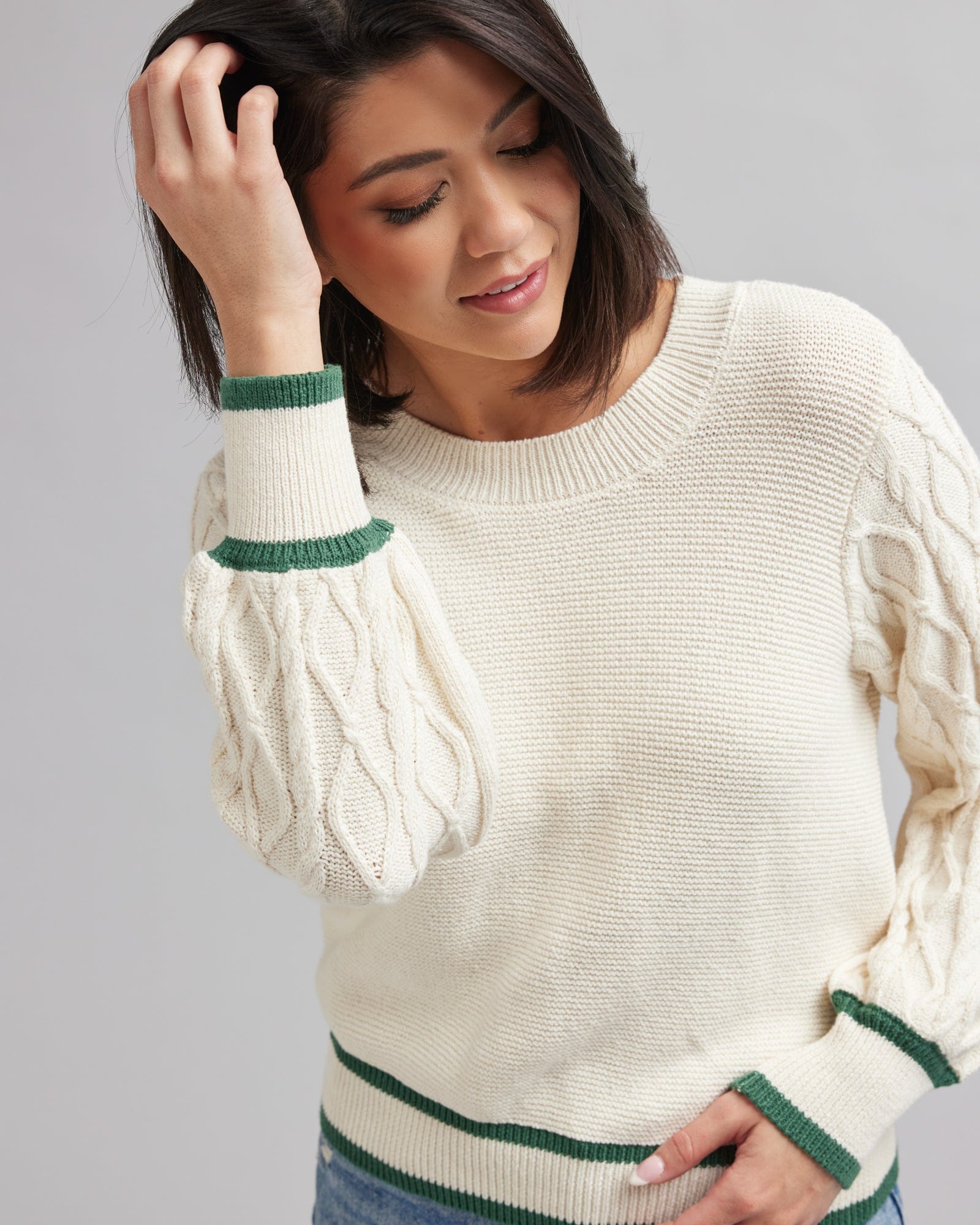 Woman in a cream colored sweater with green accents