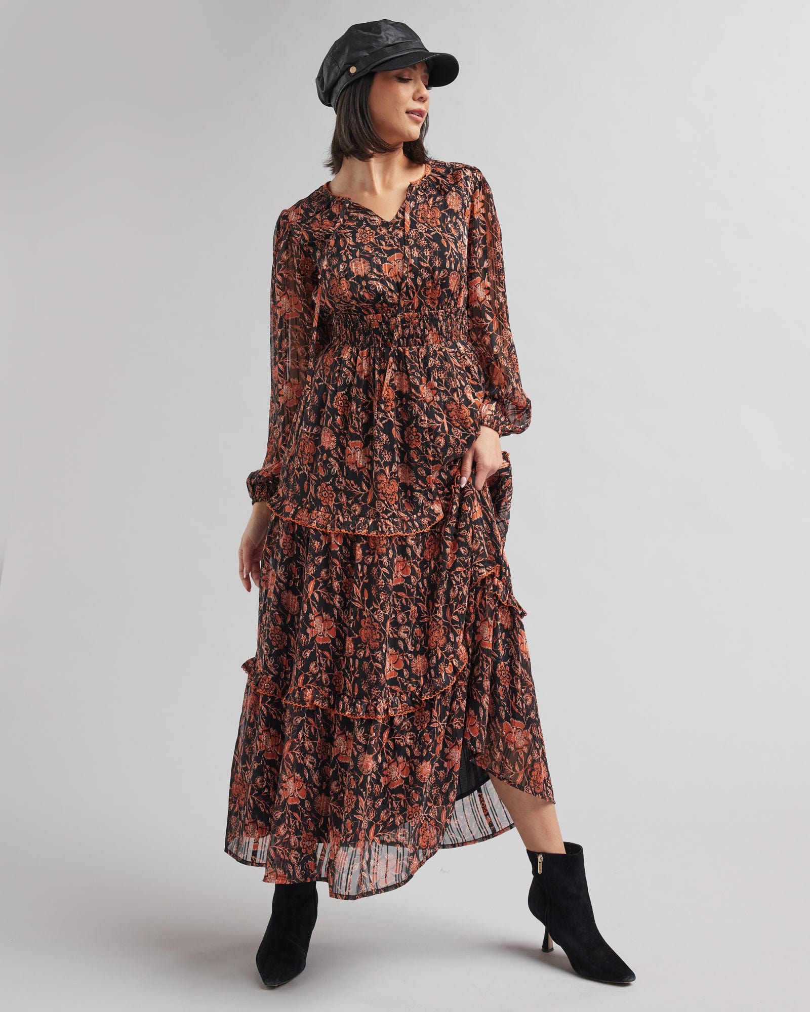 Woman in a long sleeve, maxi length, black and orange floral print dress