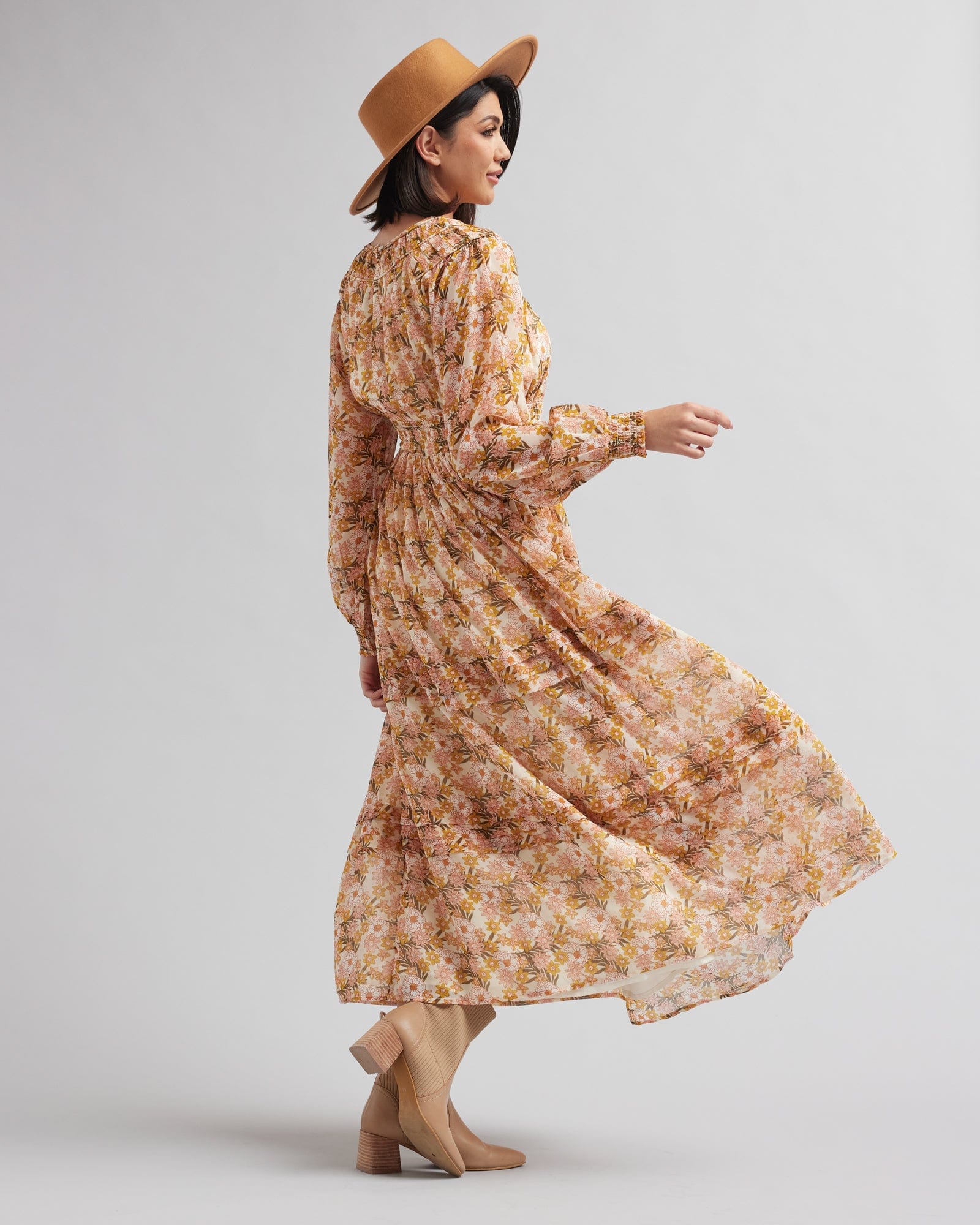Woman in a long sleeve, tan floral printed maxi dress