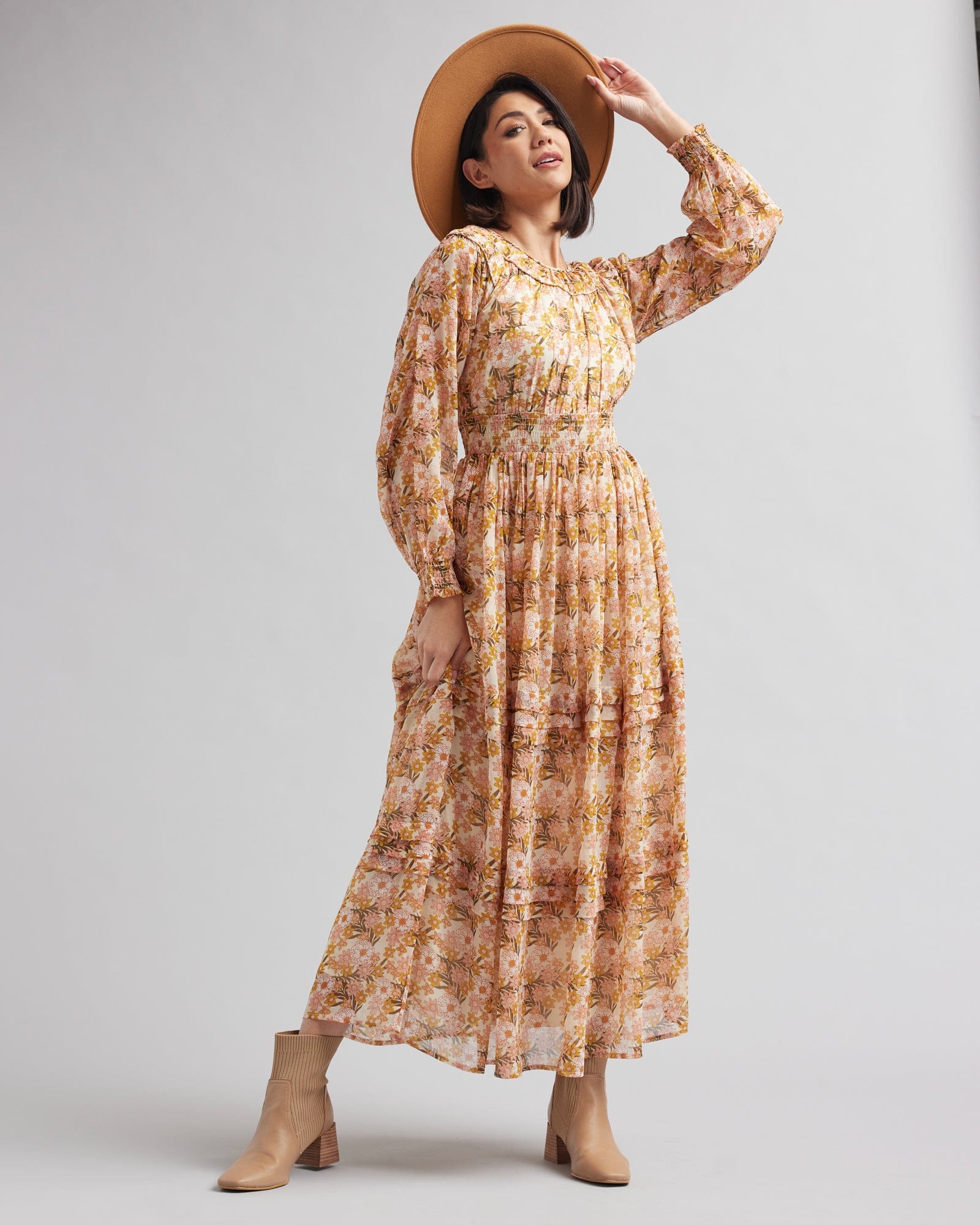 Woman in a long sleeve, tan floral printed maxi dress