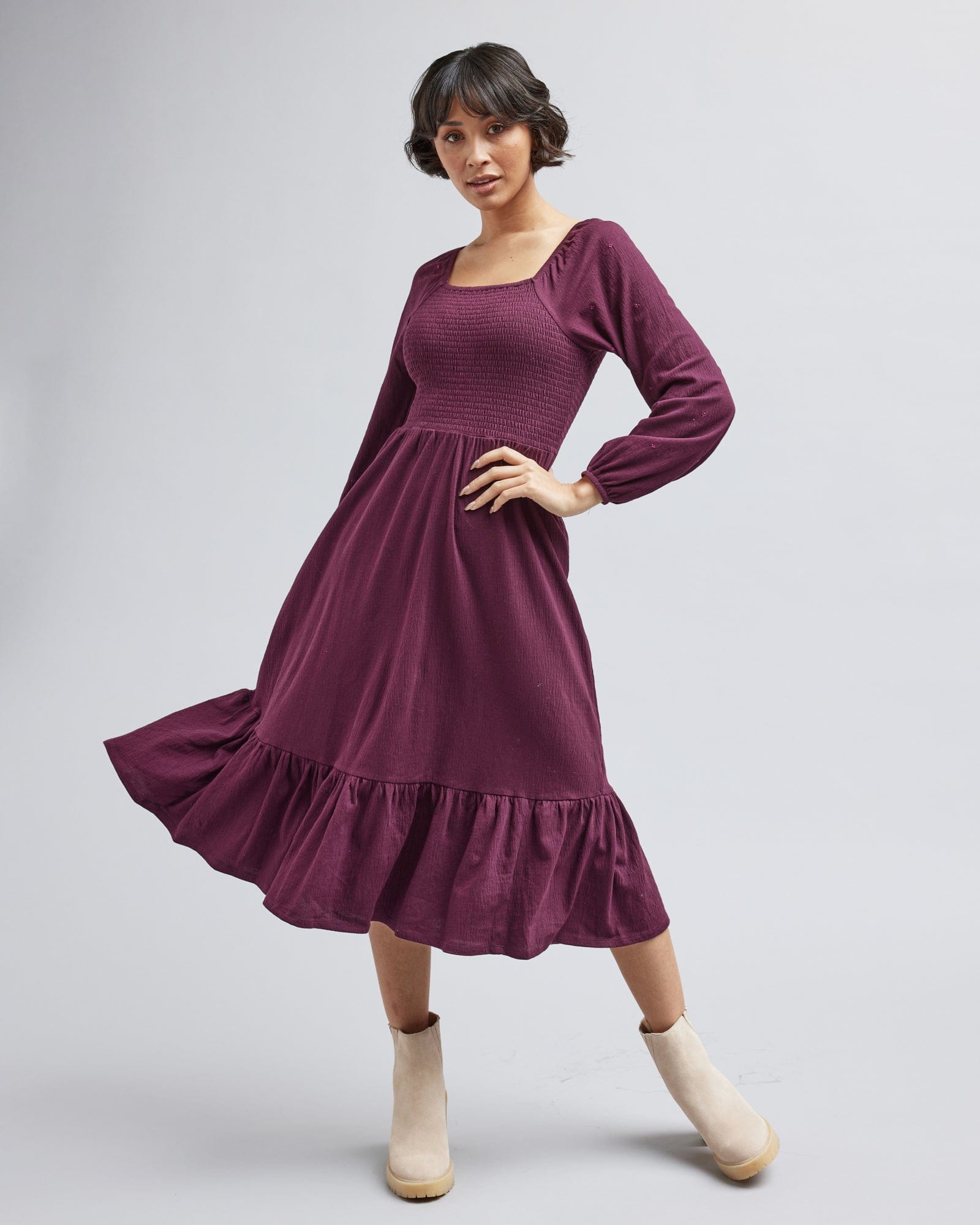 Woman in a long sleeve, smocked bodice, purple dress