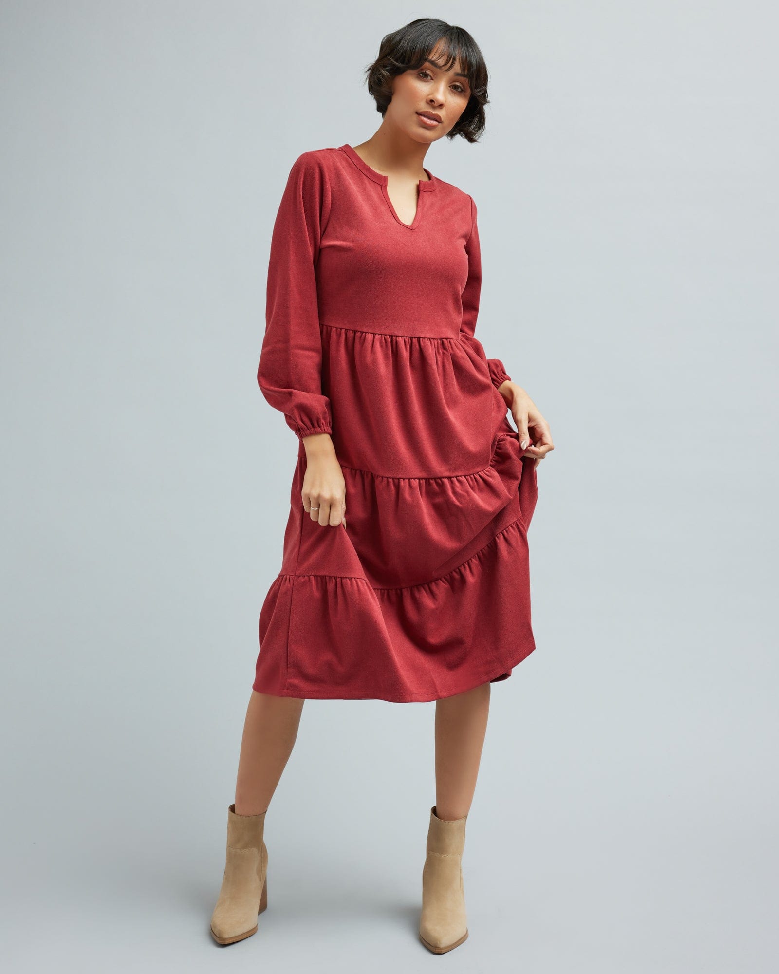 Woman in a long sleeve, tiered skirt, brick red dress.