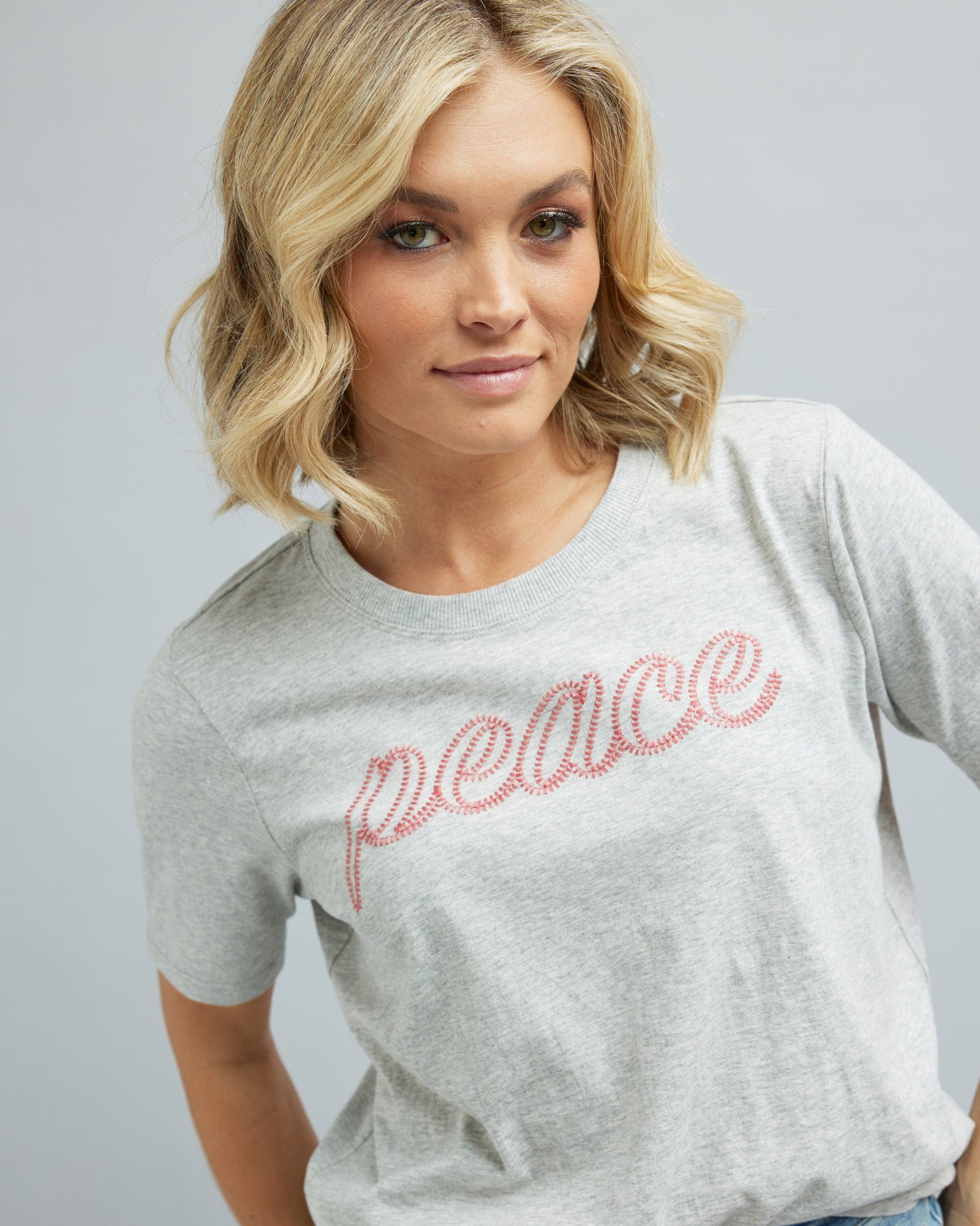 Woman in a short sleeve graphic tee that says "peace"