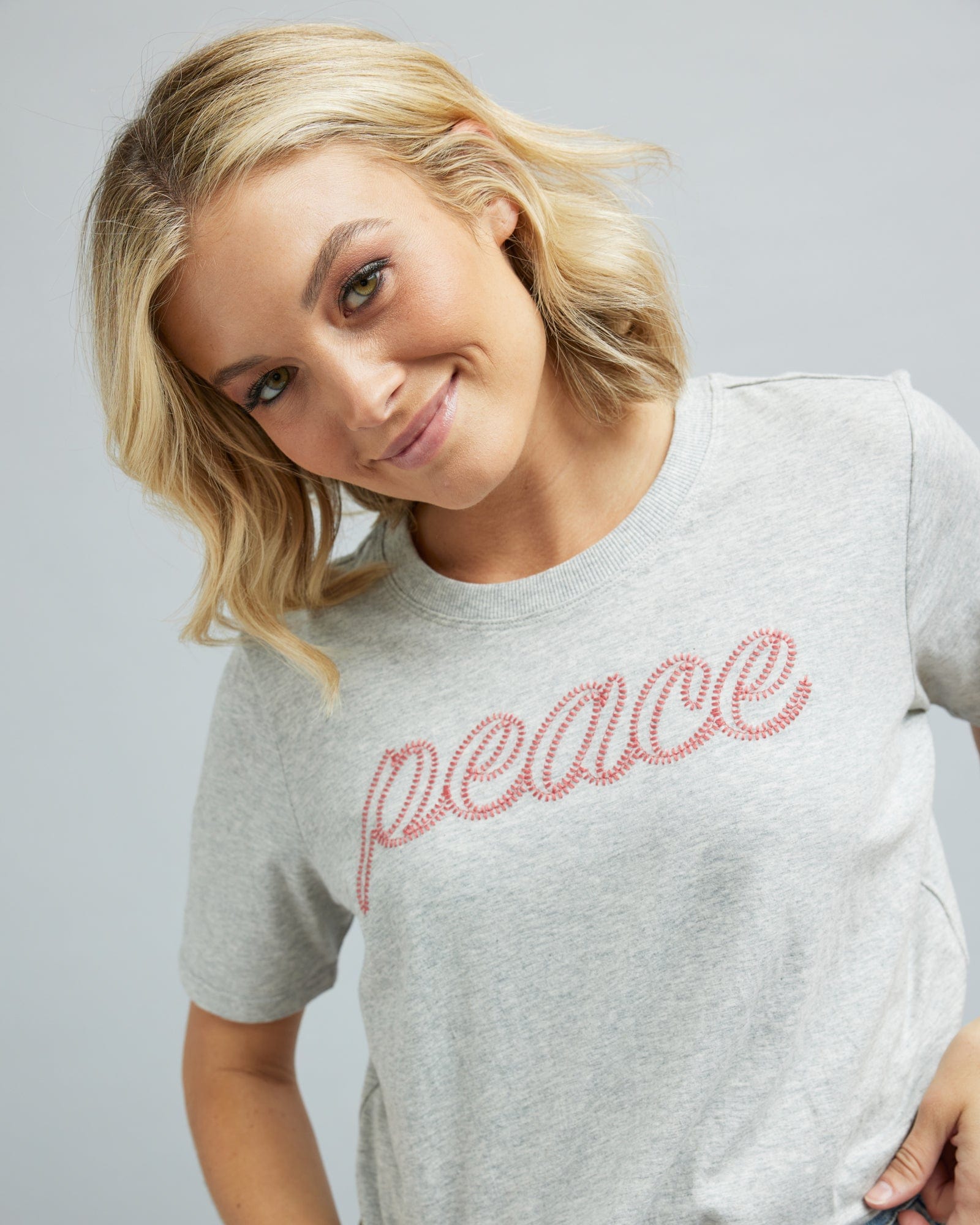 Woman in a short sleeve graphic tee that says "peace"