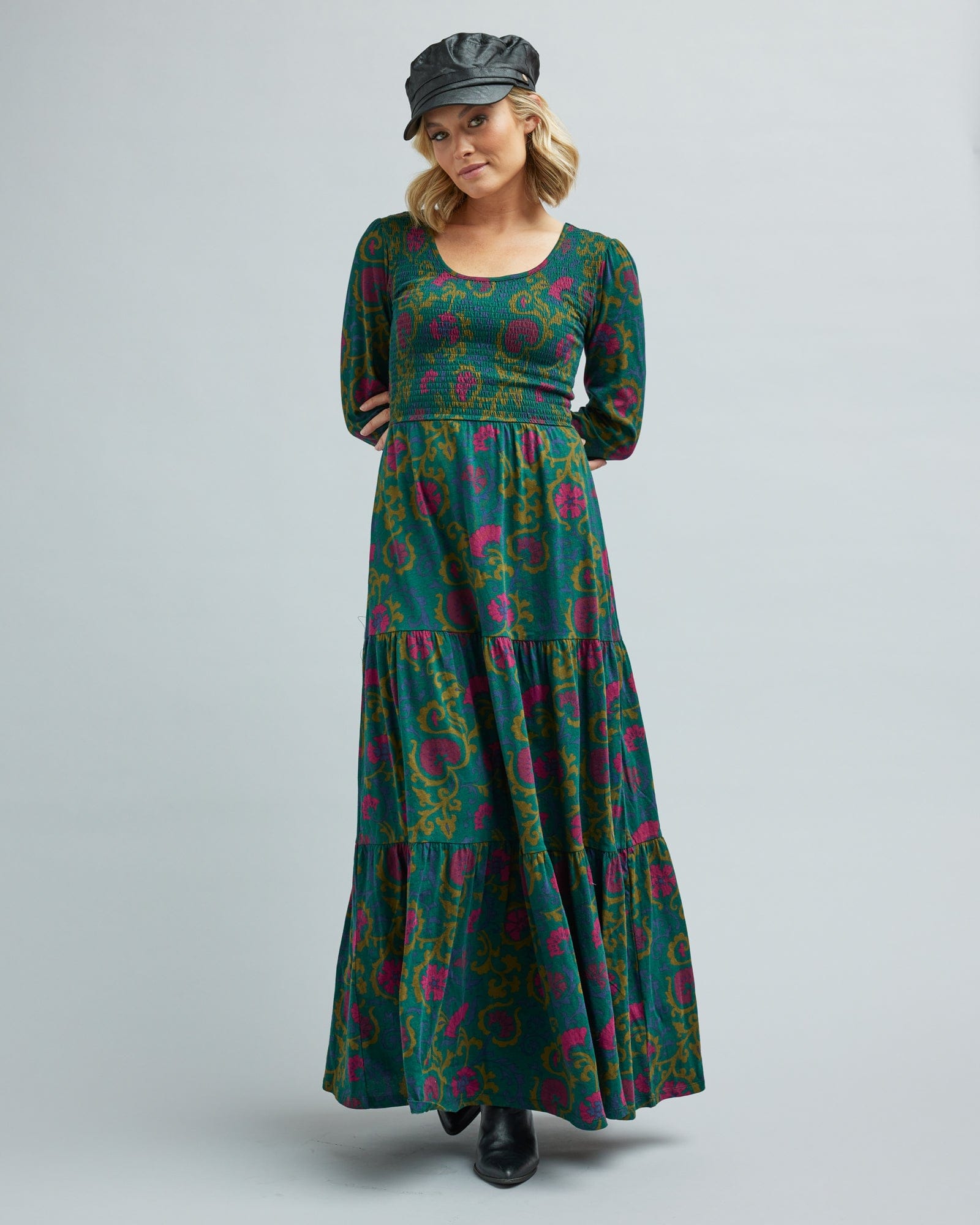 Woman in a long sleeve, tiered maxi dress with orange and green floral print