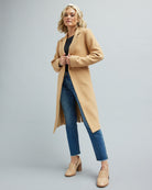 Woman in a tan color, long sleeve, belted coat