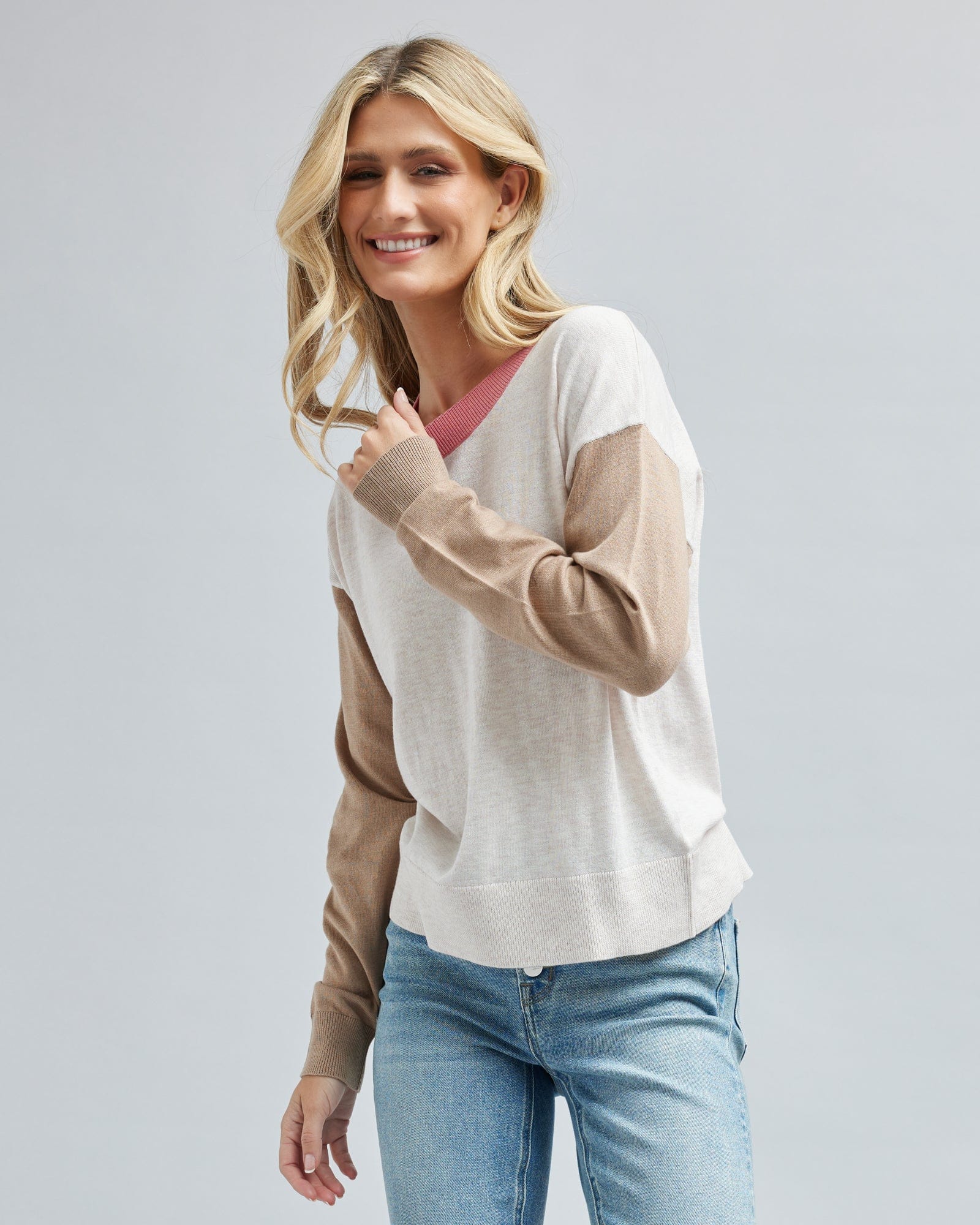 Woman in a tan and white color blocked long sleeve sweater.