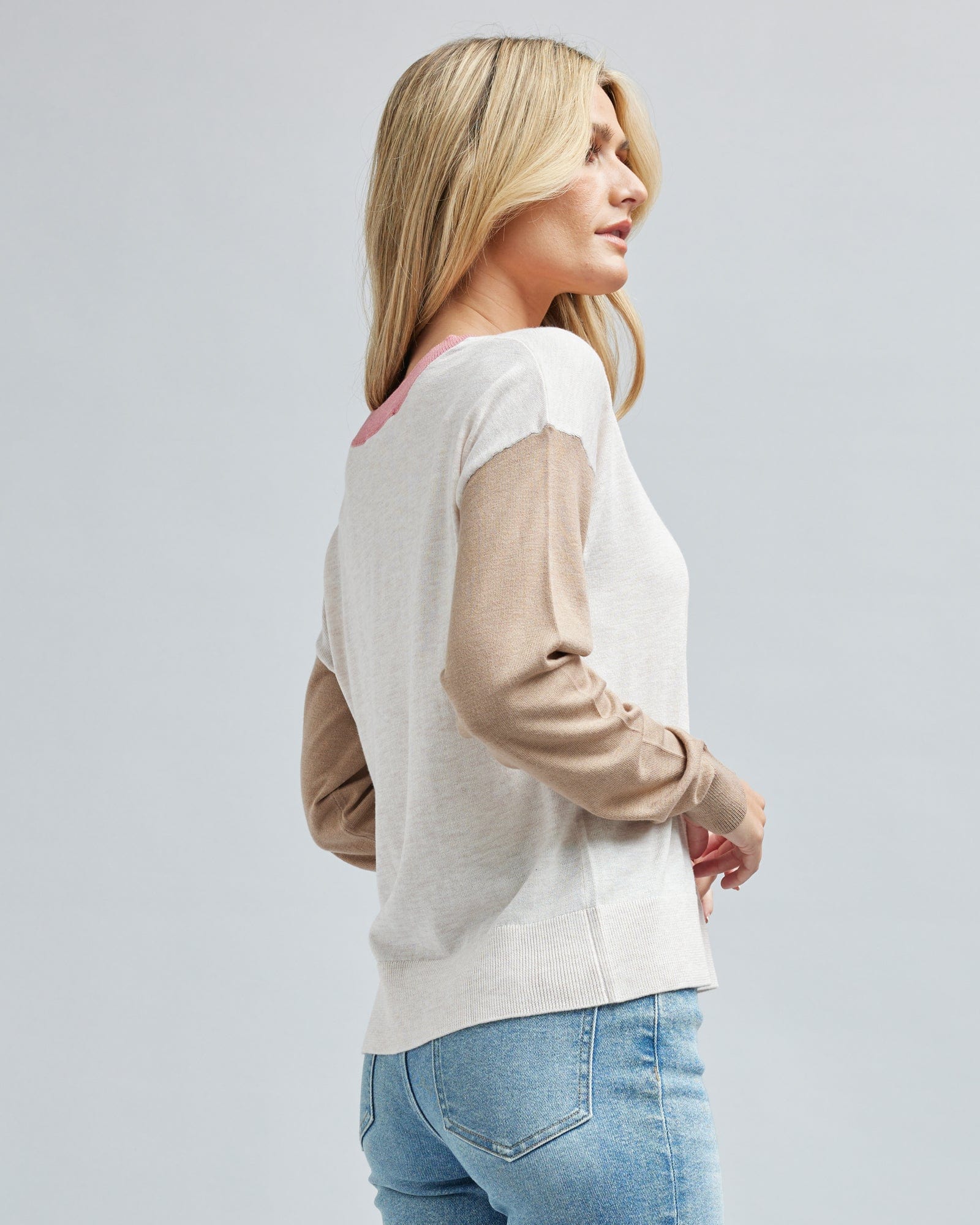 Woman in a tan and white color blocked long sleeve sweater.