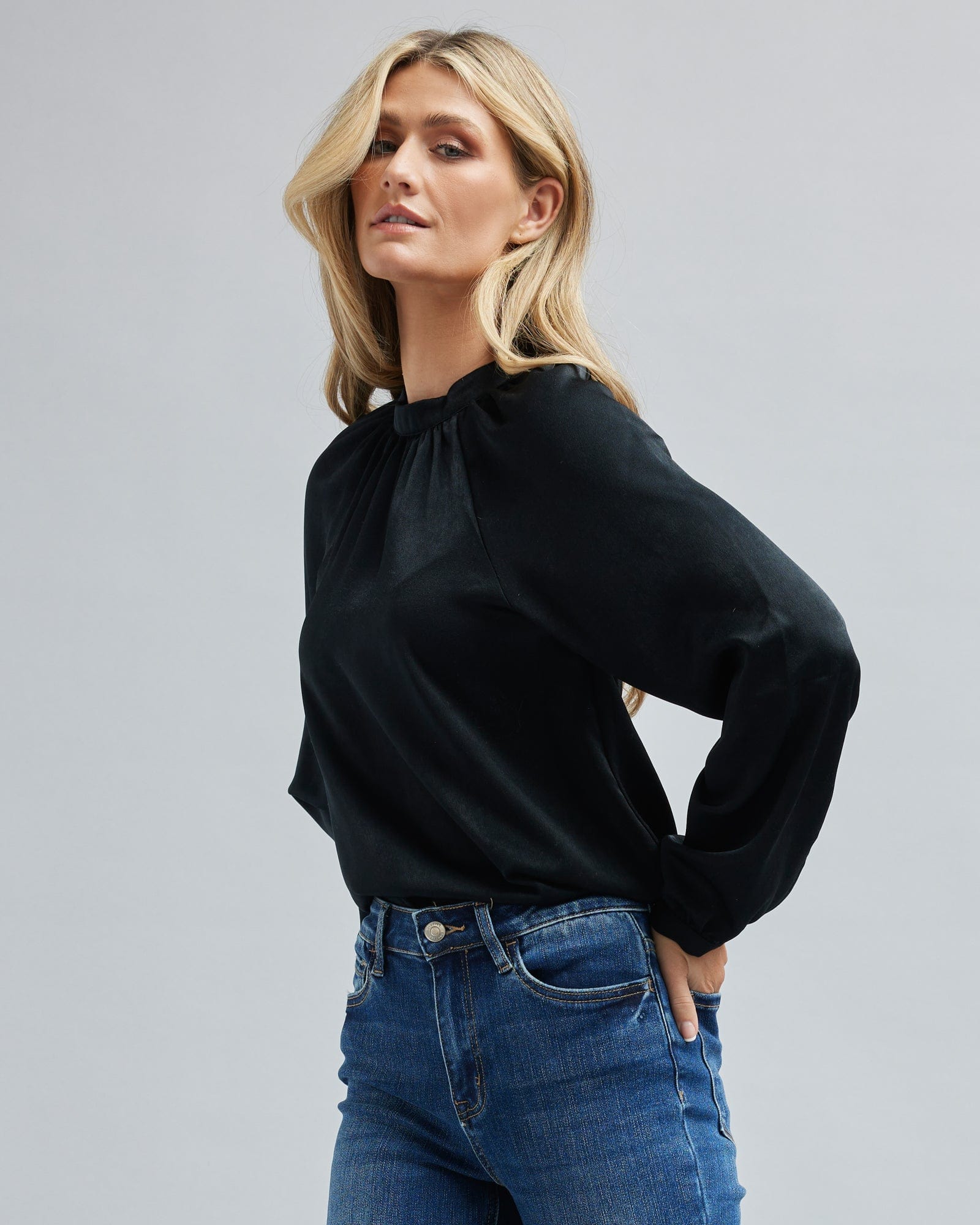 Woman in a high neck, long sleeved, black blouse