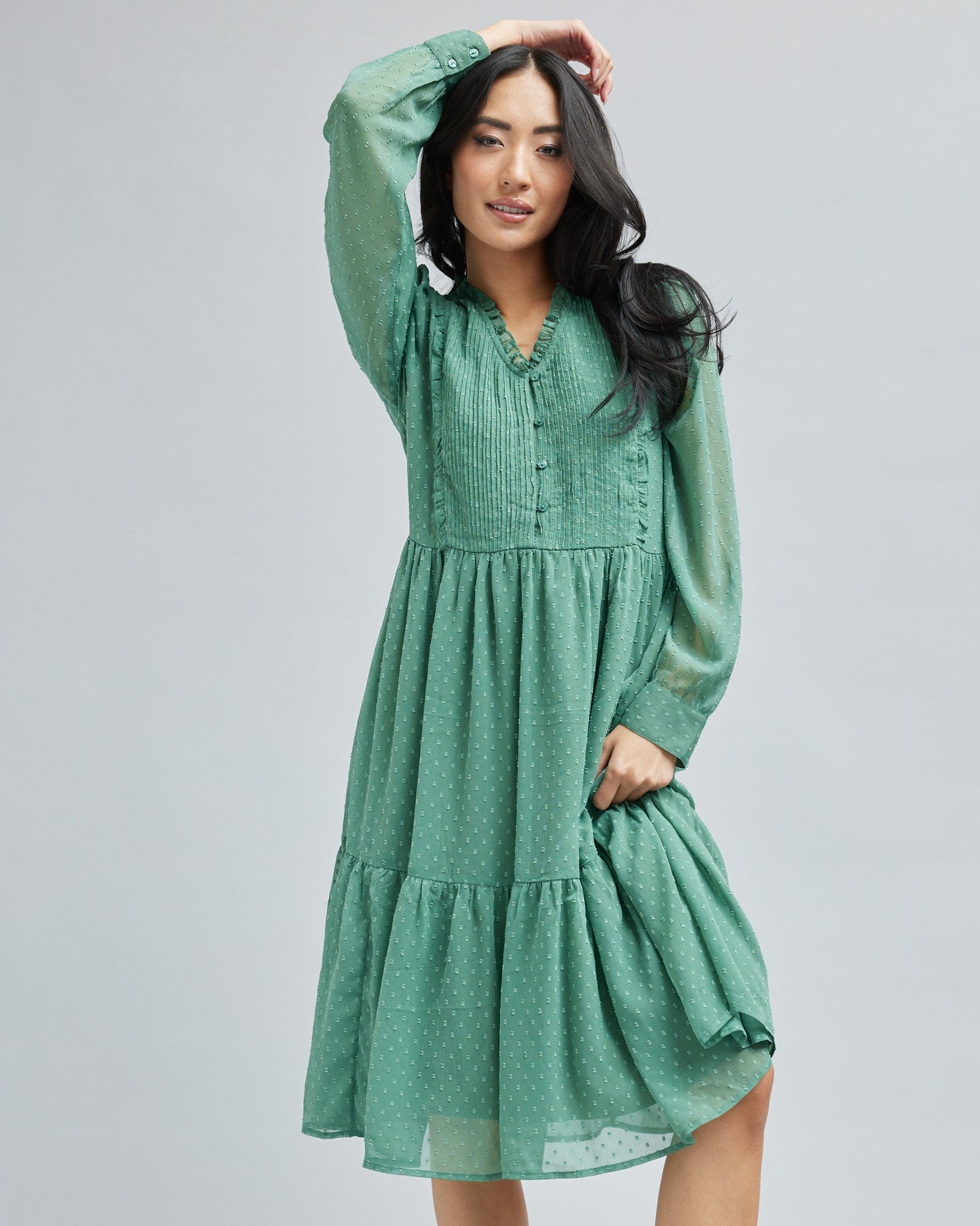 Woman in a long sleeve, green, midi length dress