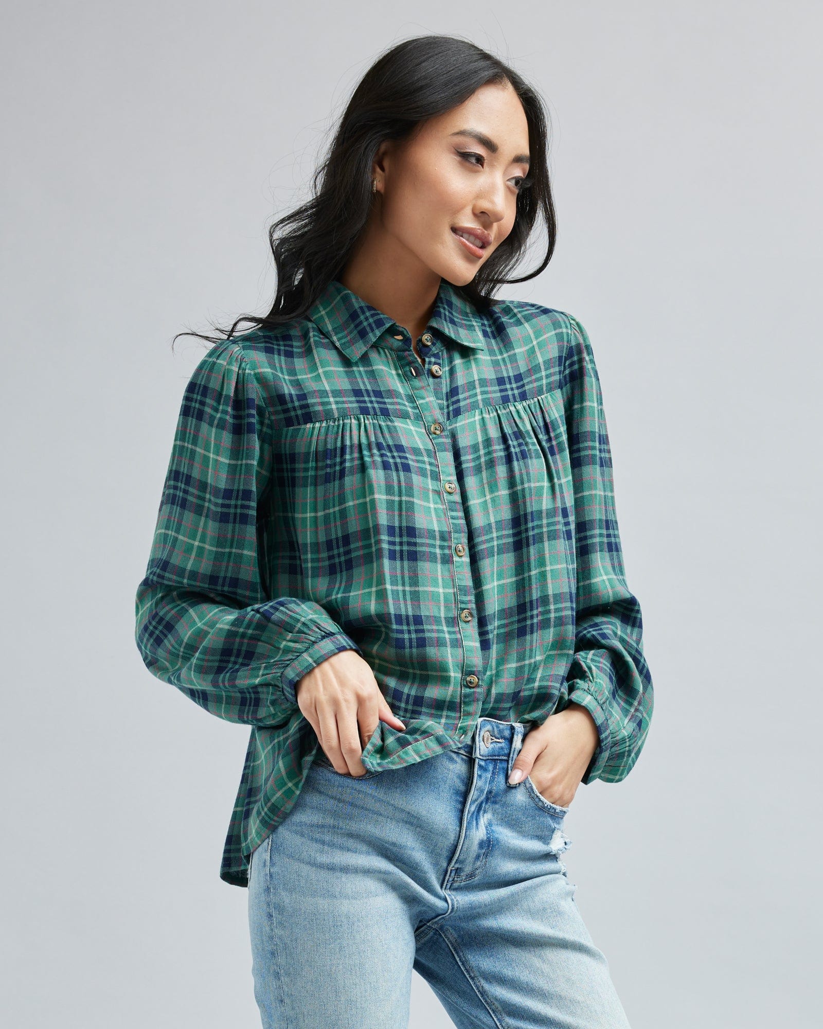 Woman in a collared, blue and green plaid, long sleeve blouse