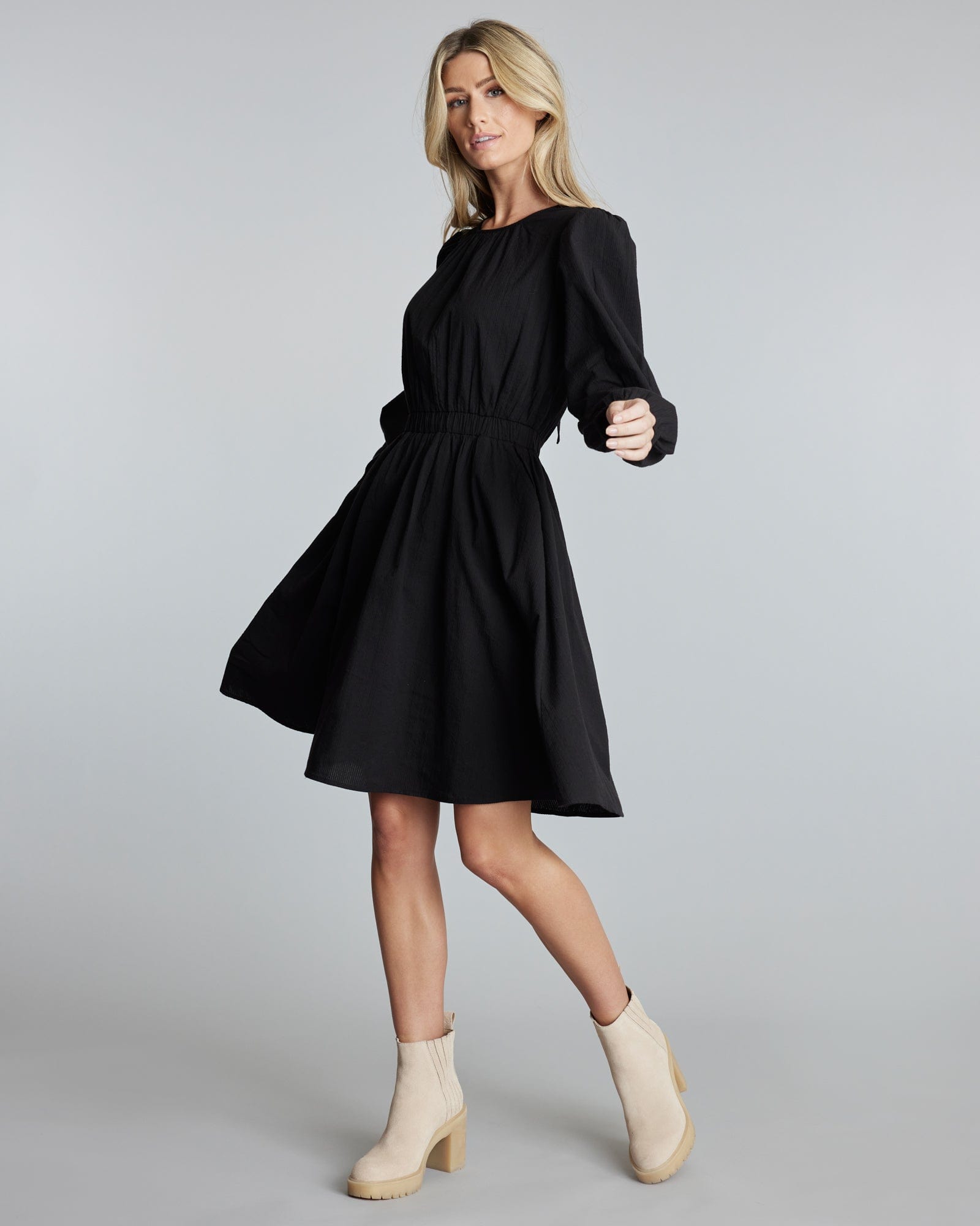 Woman in a black long sleeve, knee-length dress.