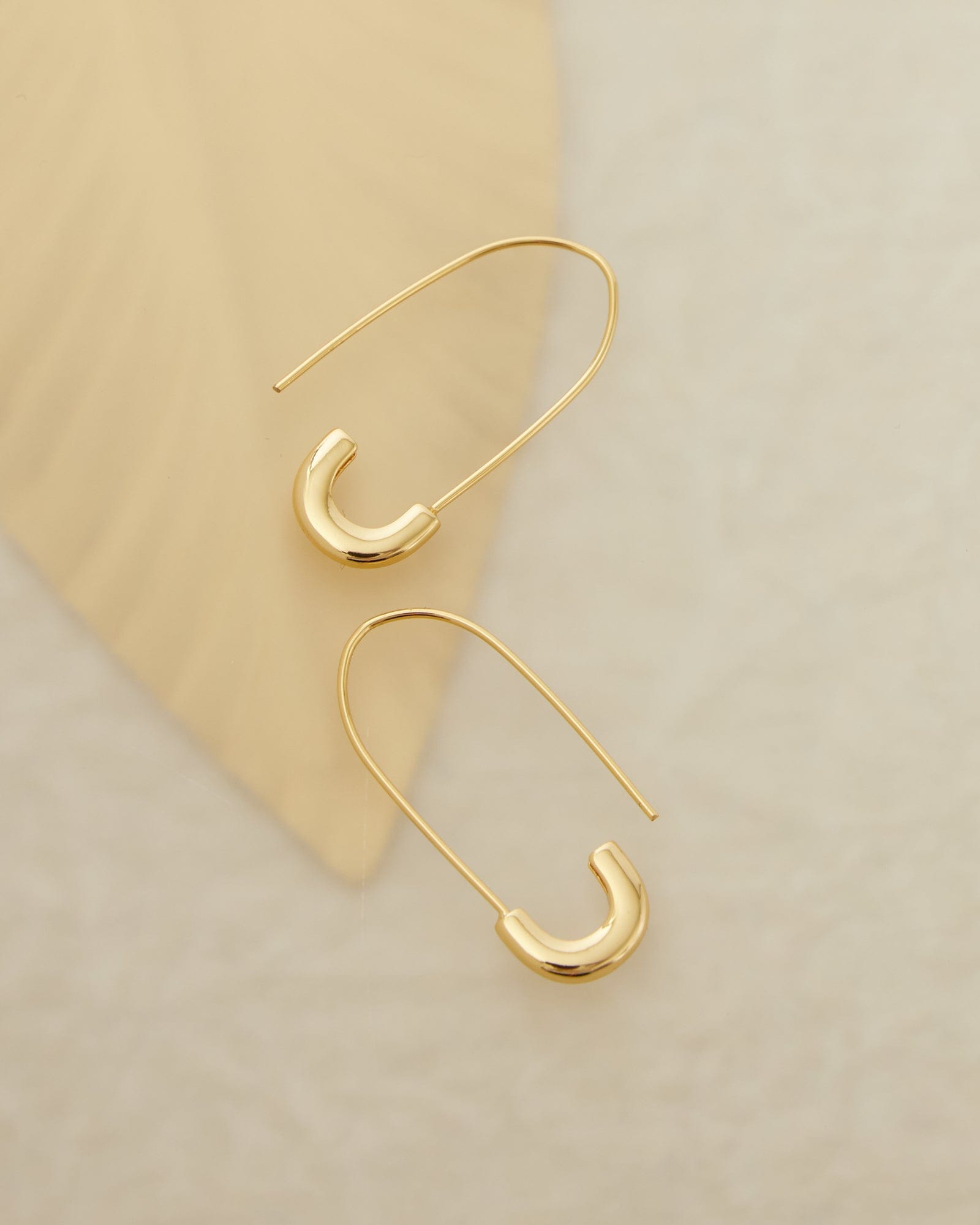 Two gold earrings resembling safety pins