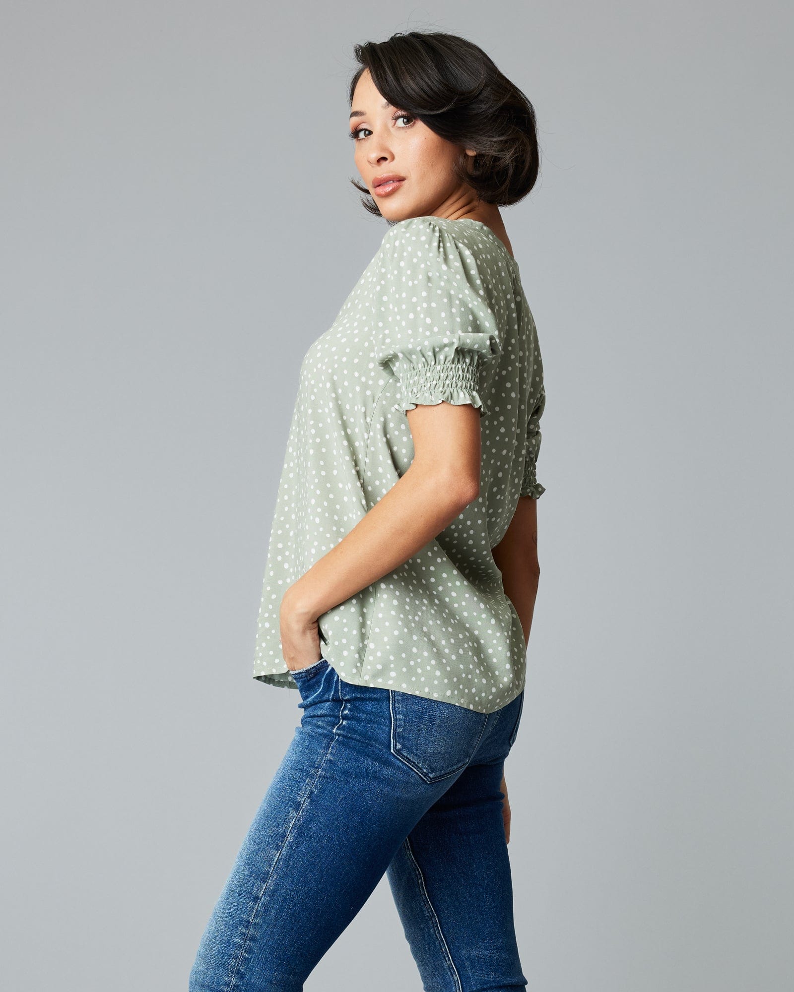Woman in a short sleeve, green, polka dotted blouse.