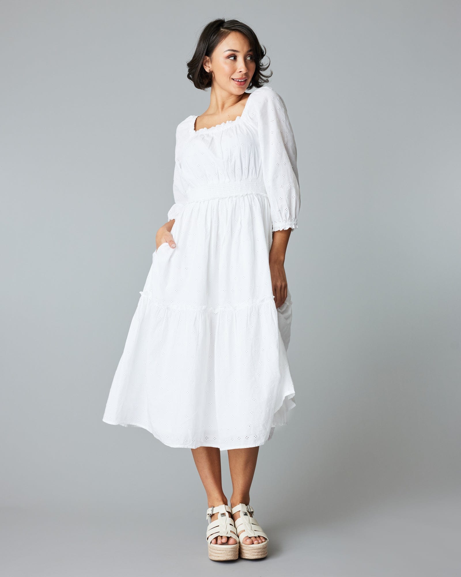 Woman in a white, eyelet midi length dress
