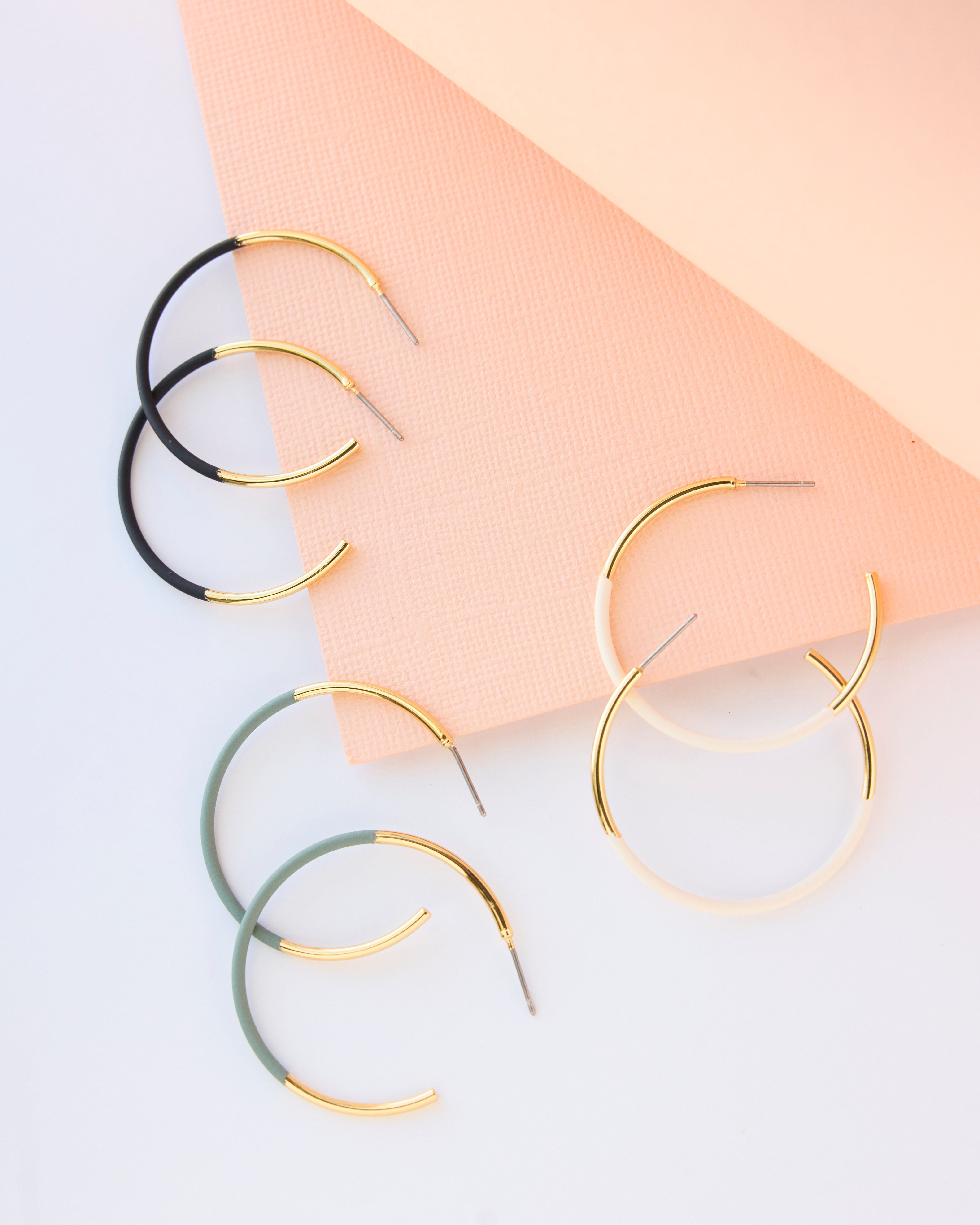 Three-piece earring set of hoops in gold, green, black and white.