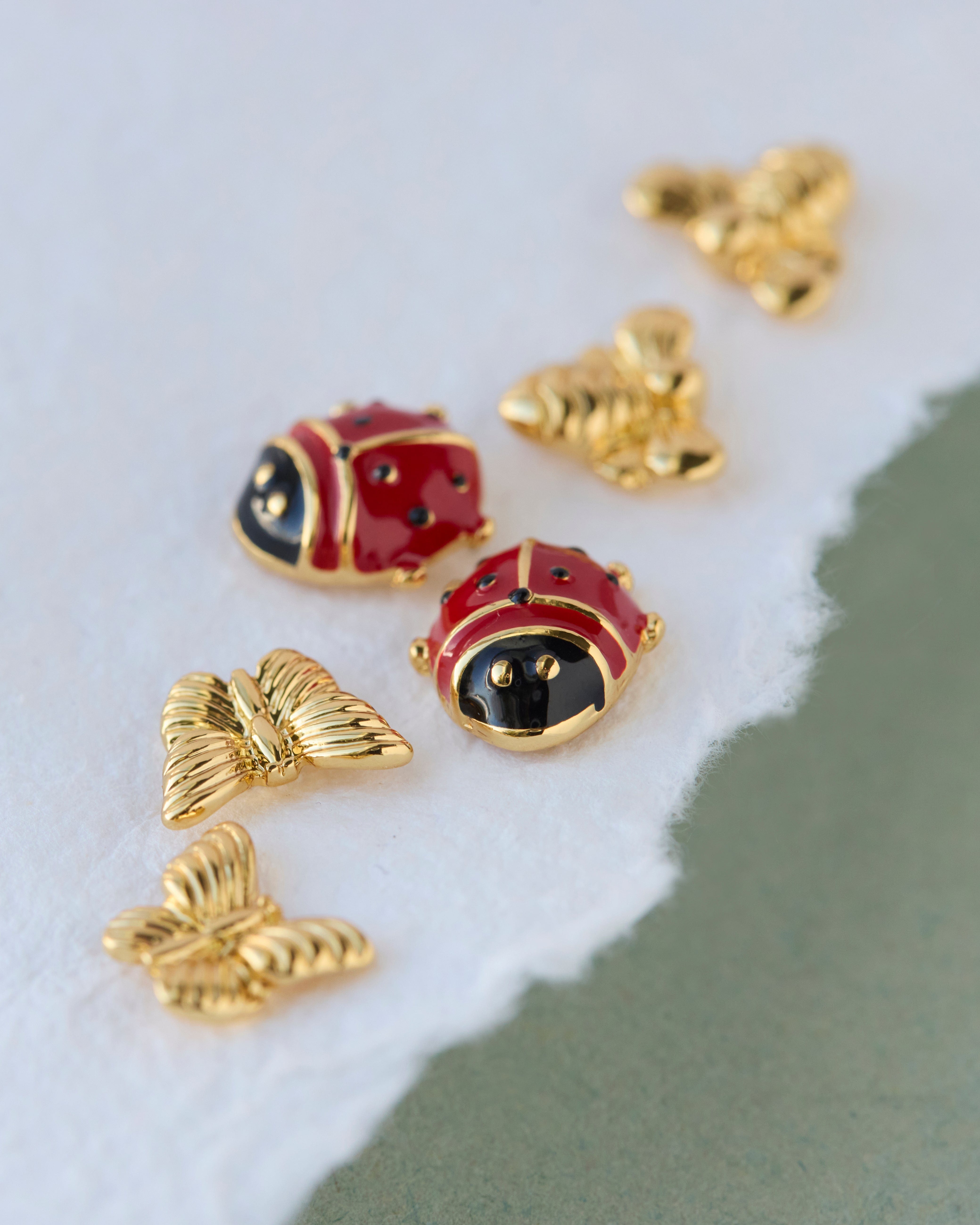 Three-piece earring set of gold butterflies, gold bees, red ladybugs.