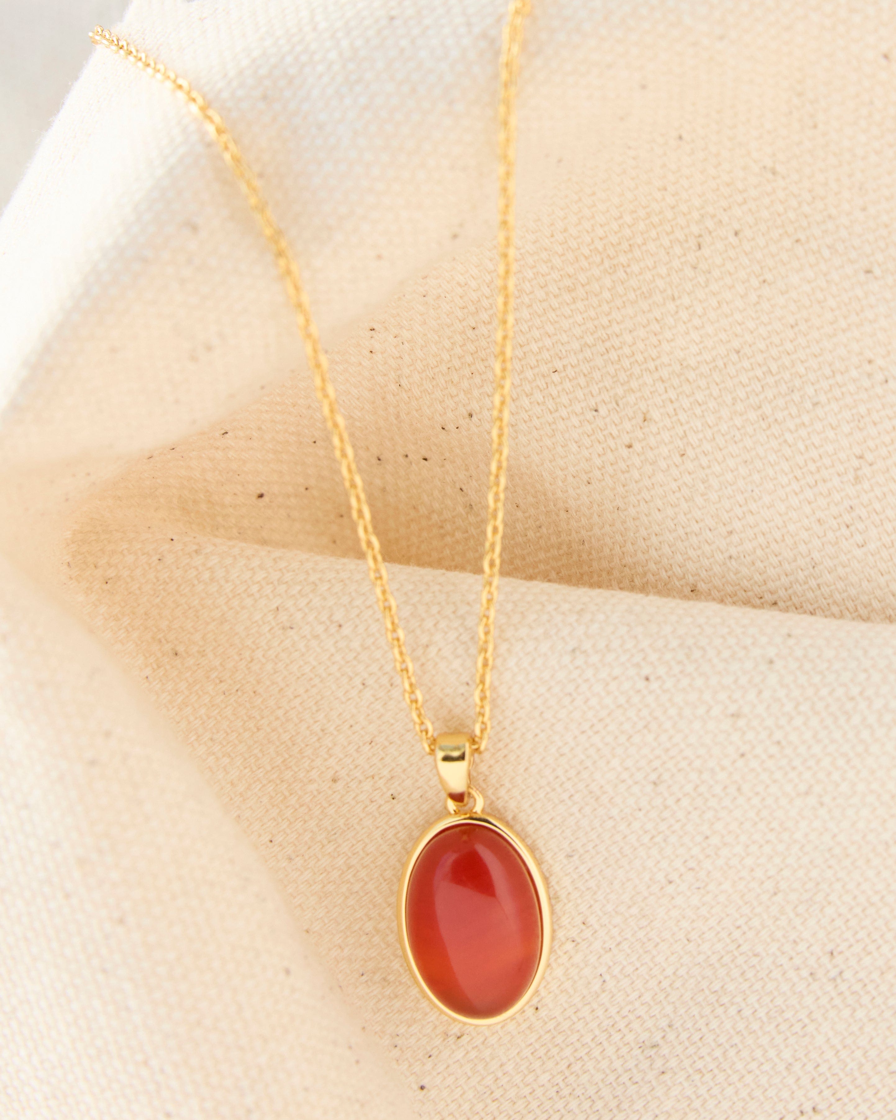 Gold necklace with a brown stone pendant.