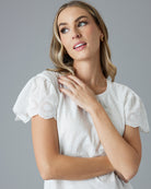 Woman in a white, short sleeved t-shirt with eyelet detail on sleeves.