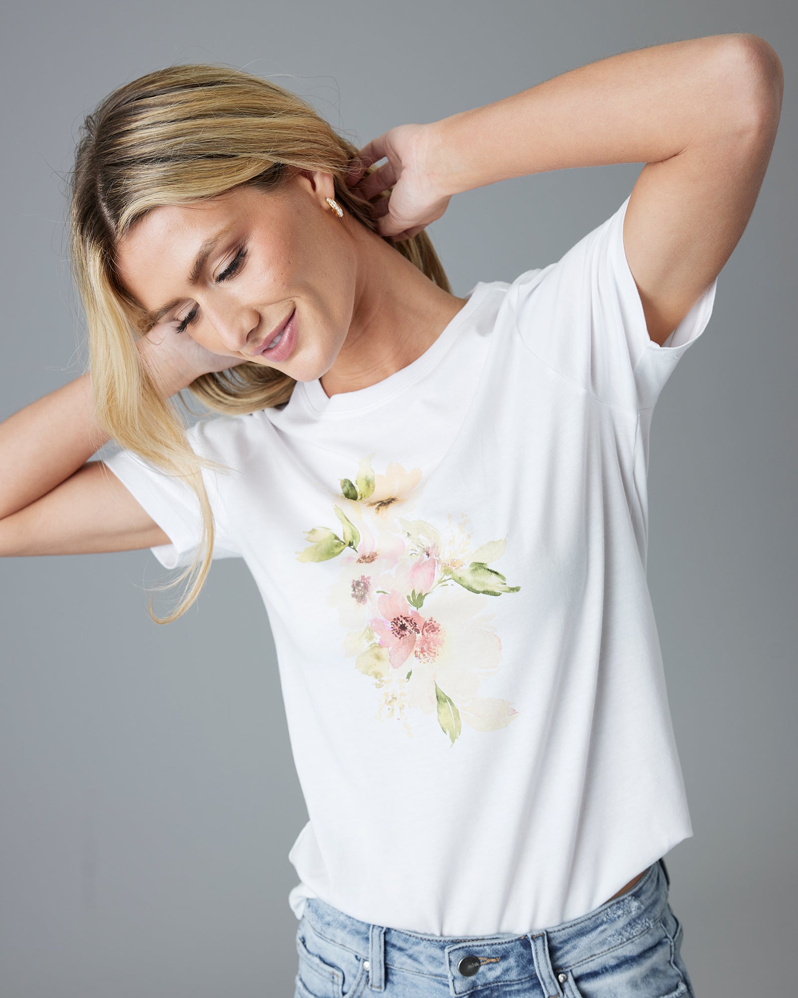 Woman in a white graphic tee with a watercolor flower on the top