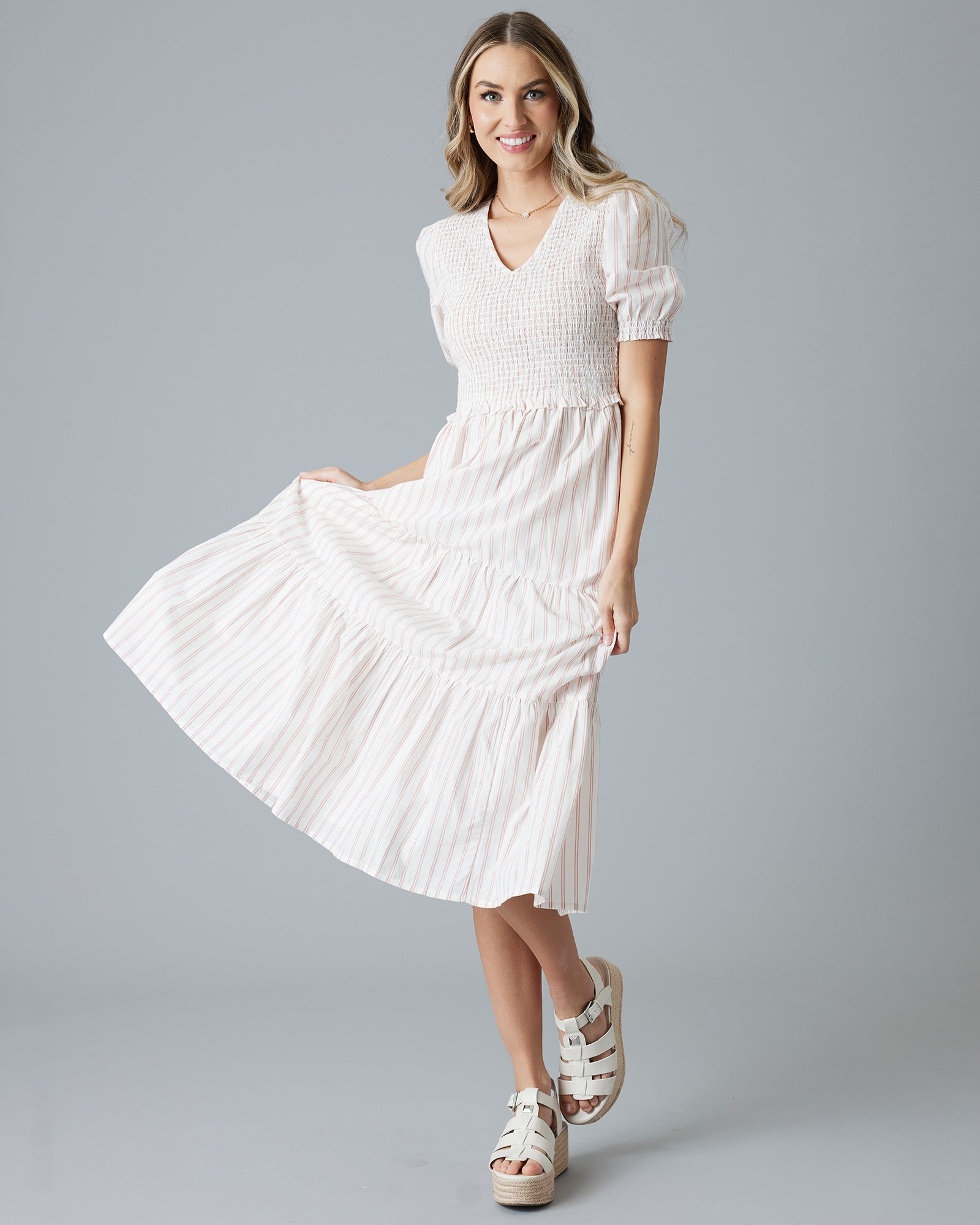 Woman in a white with pink vertical striped, short sleeve midi-length dress
