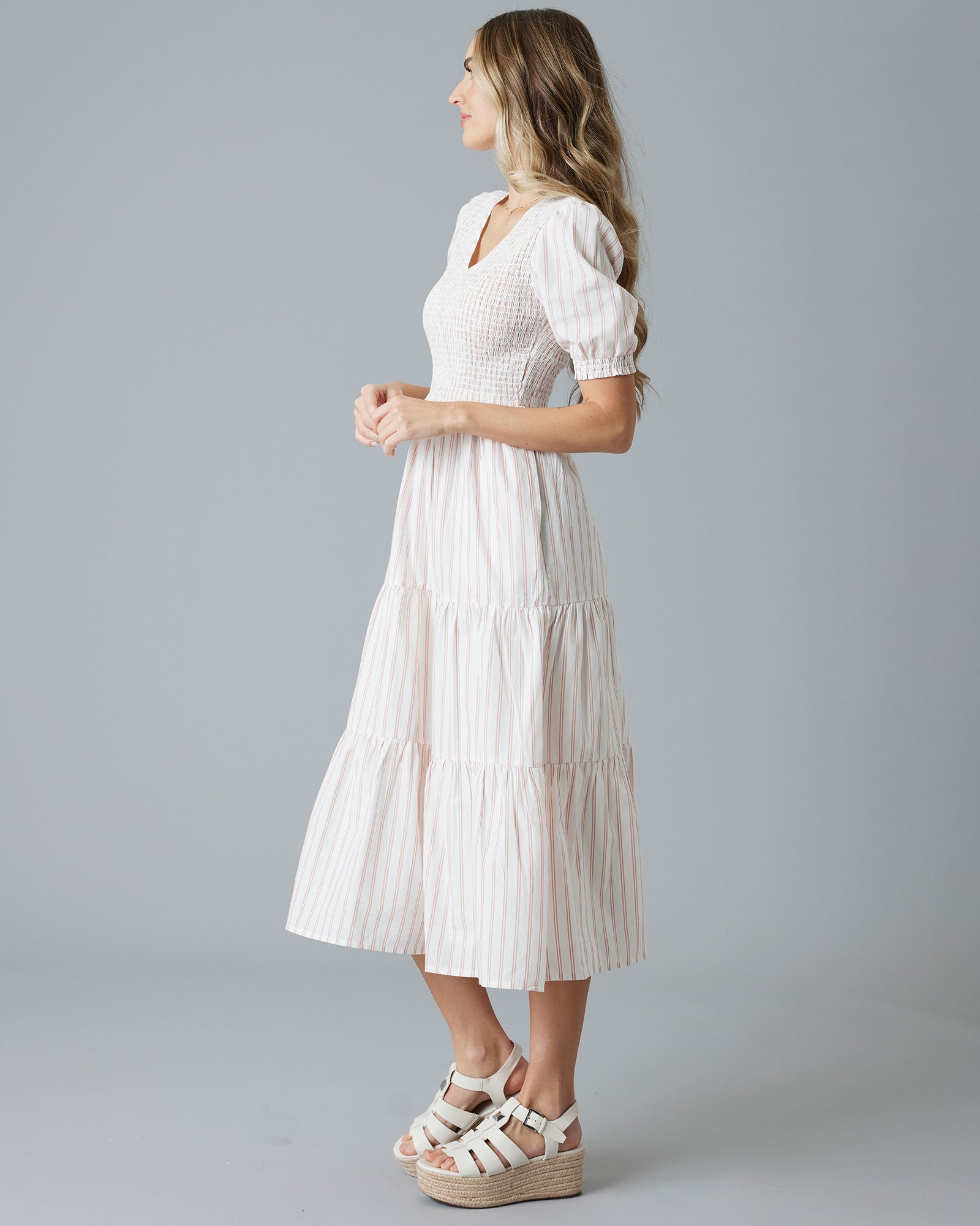 Woman in a white with pink vertical striped, short sleeve midi-length dress