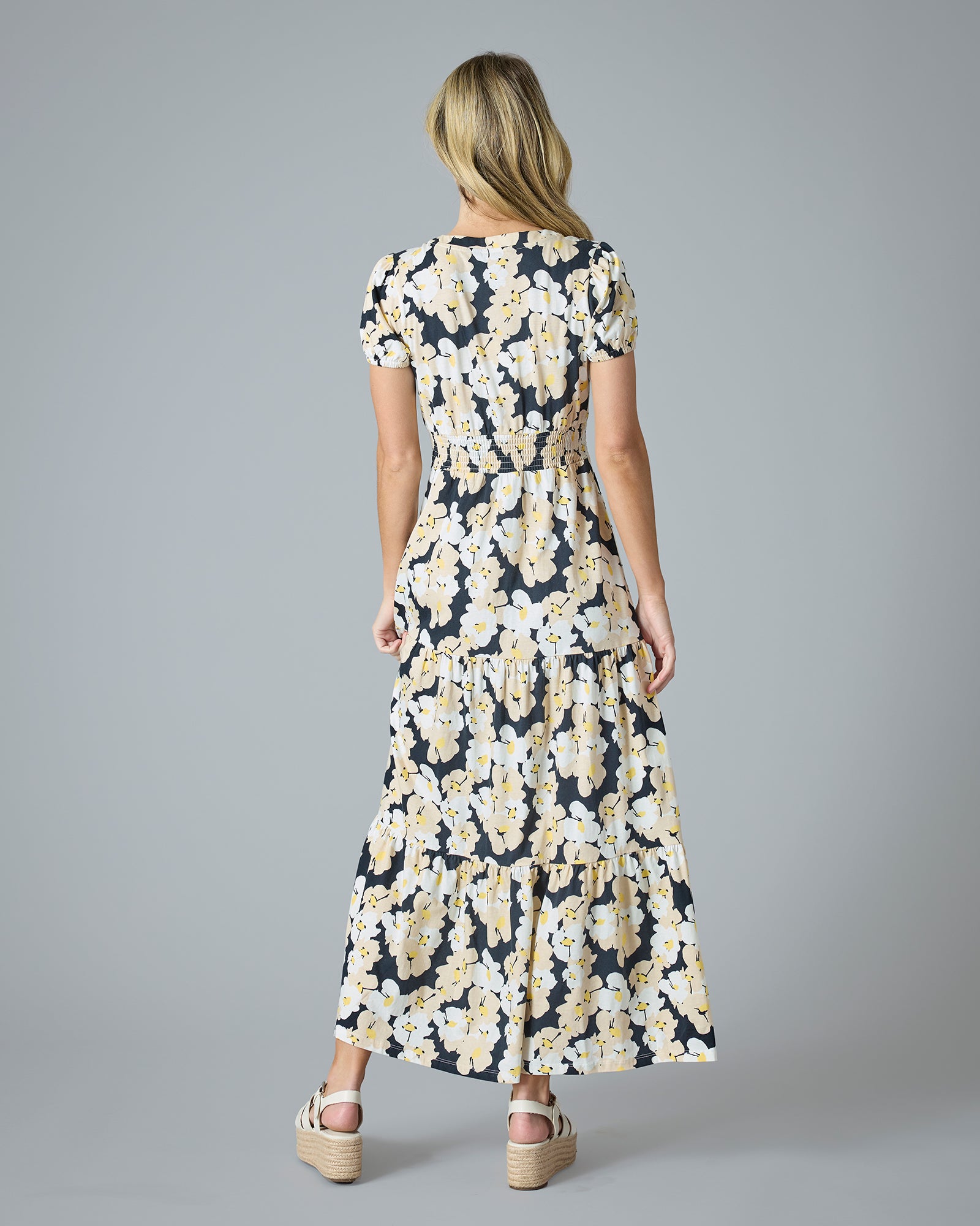 Woman in a navy, white and yellow floral printed short sleeve maxi dress