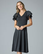 Woman in a black short sleeve, v-neck, knee-length dress