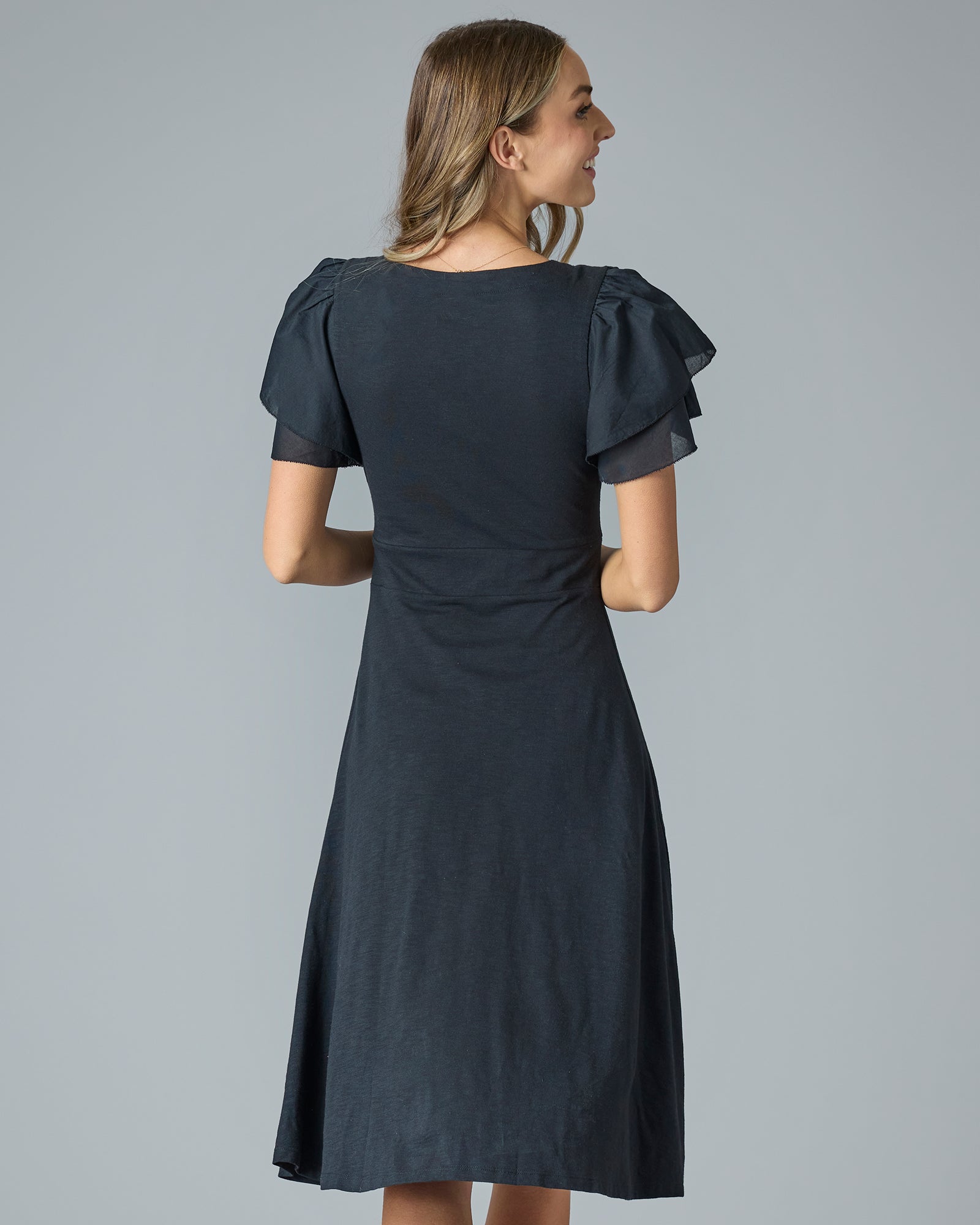 Woman in a black midi-length dress with ruffle short sleeves
