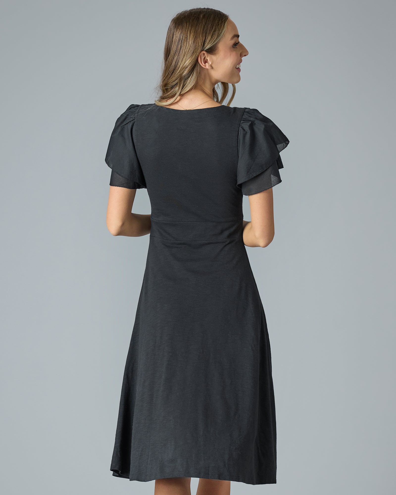 Woman in a black short sleeve, v-neck, knee-length dress