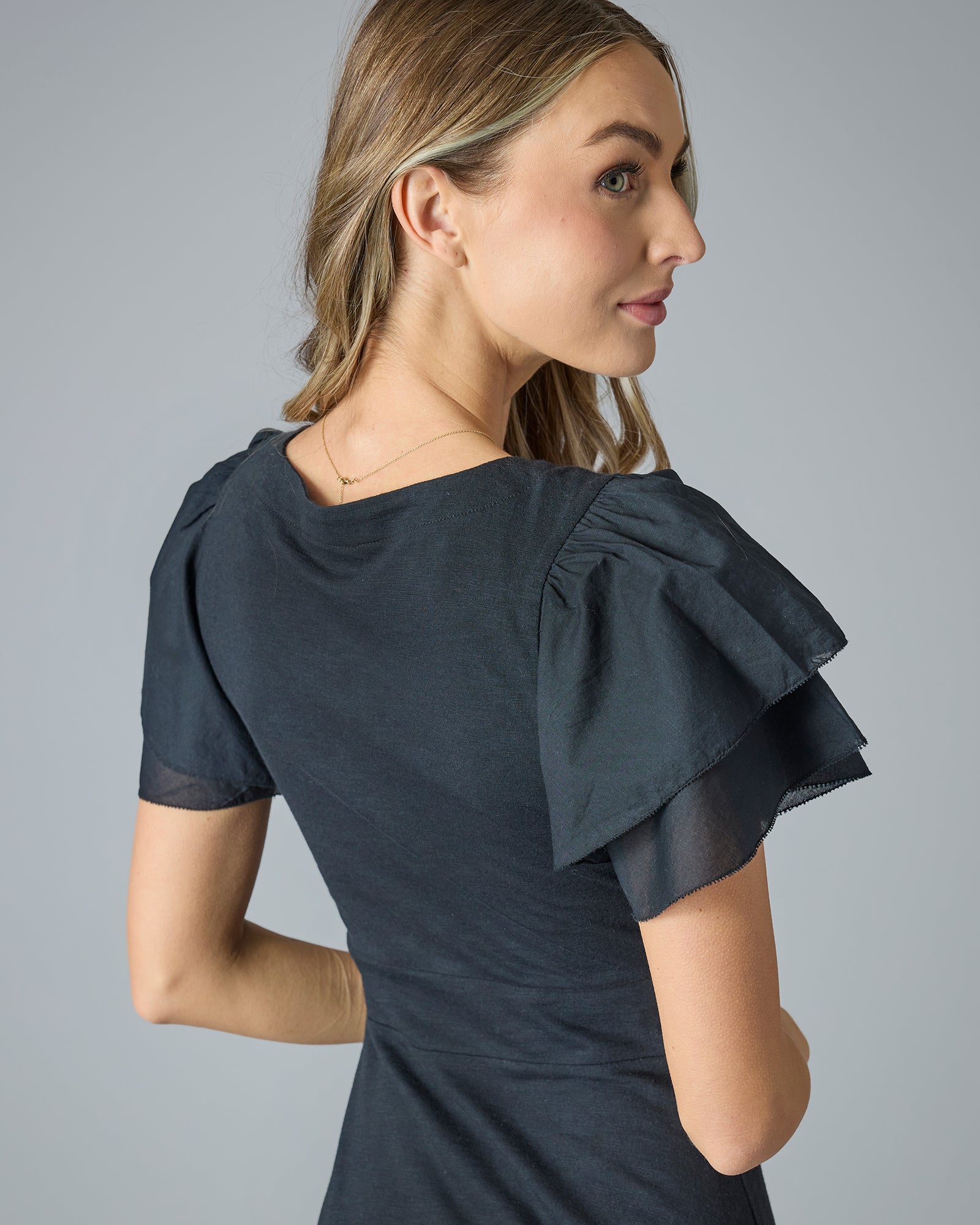 Woman in a black midi-length dress with ruffle short sleeves